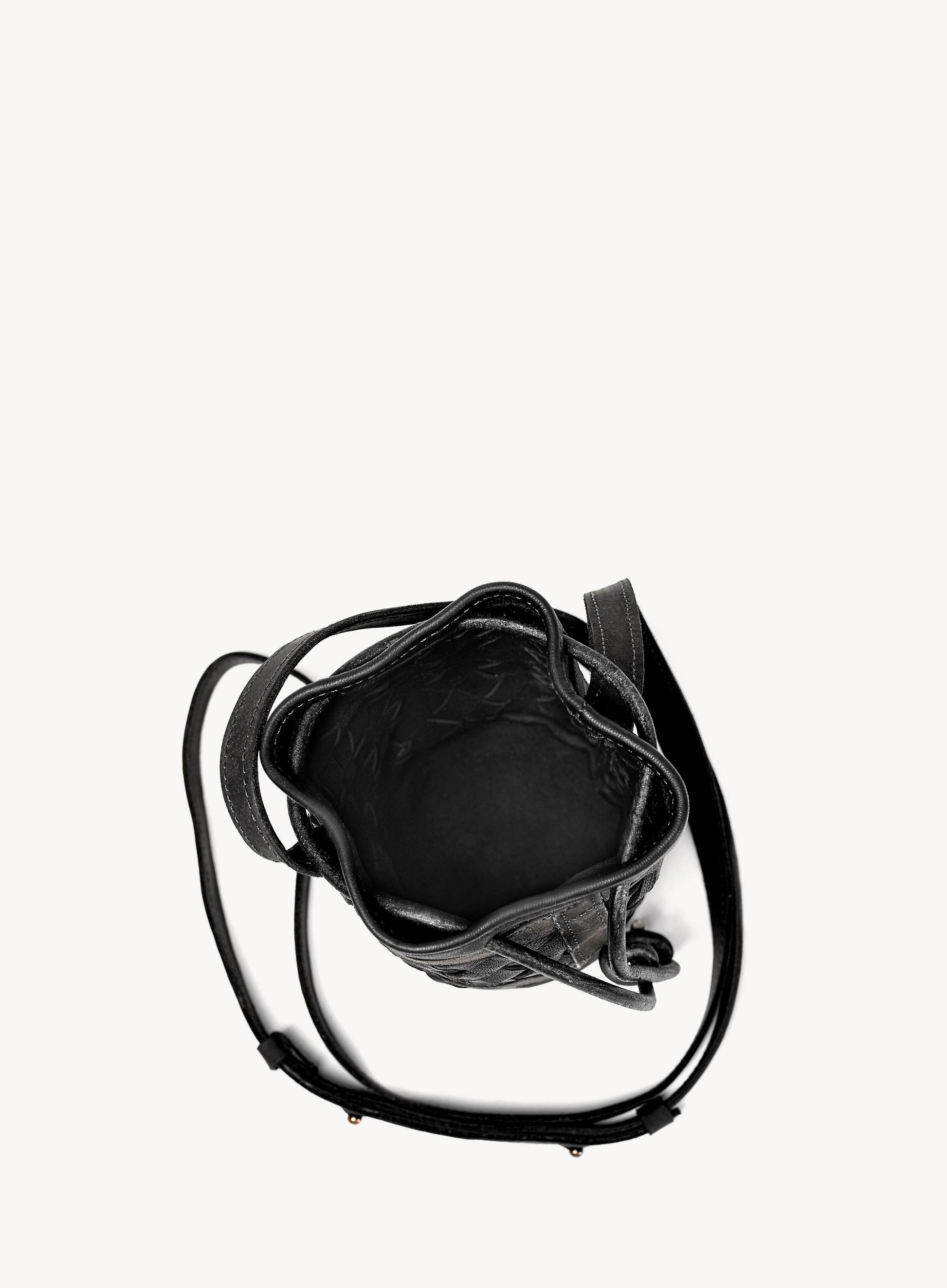 Mini essential bucket bag displayed by model holding womens handbag in black.