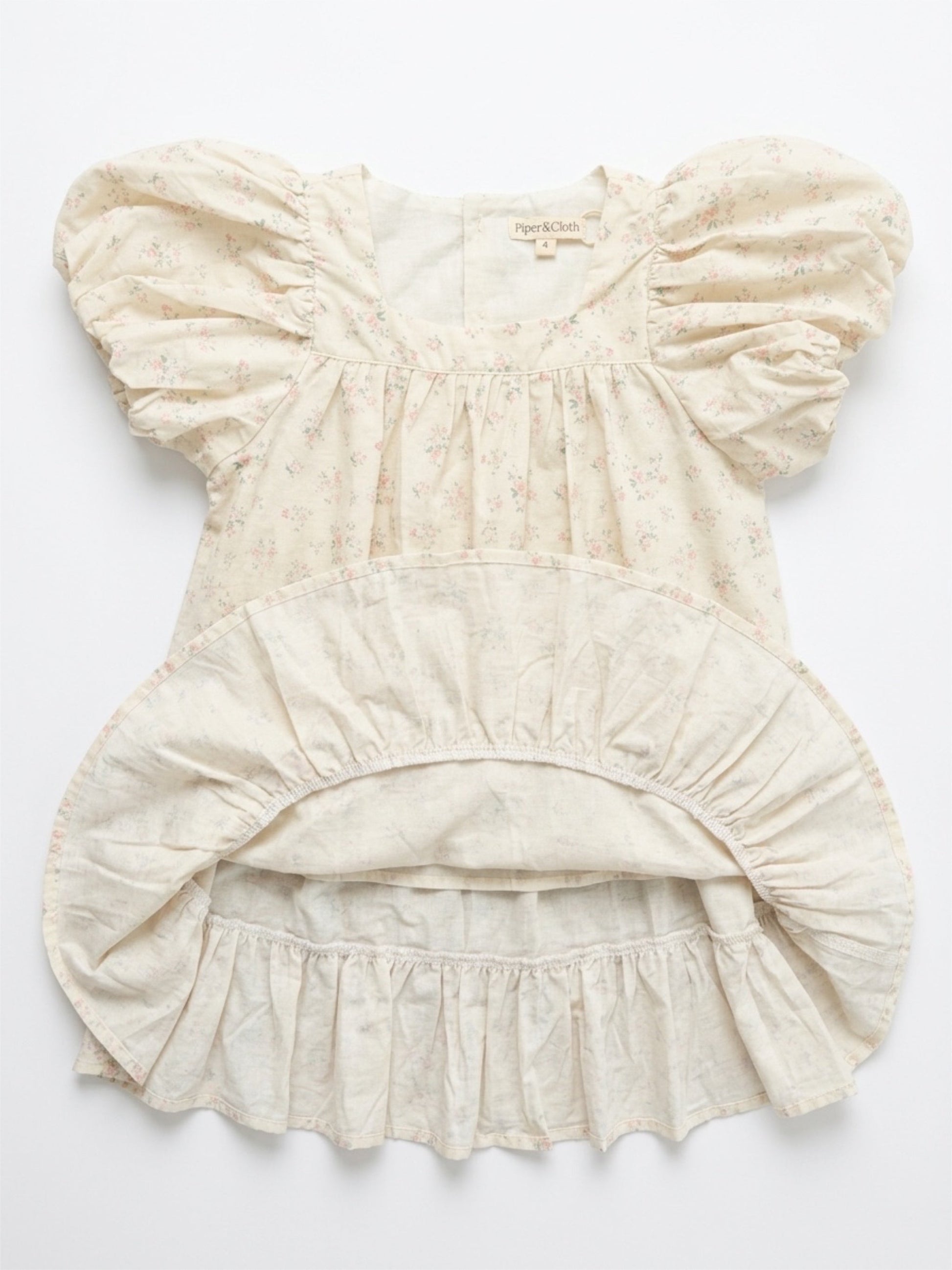 Beige baby romper with ruffled details on a white background