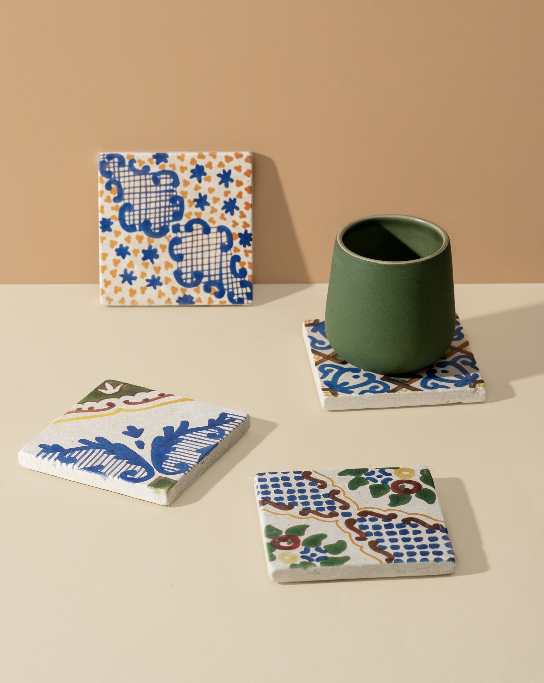 A single square white marble coaster with a blue floral pattern, displayed on a neutral background with a cup placed on top, highlighting its functional and decorative appeal.
