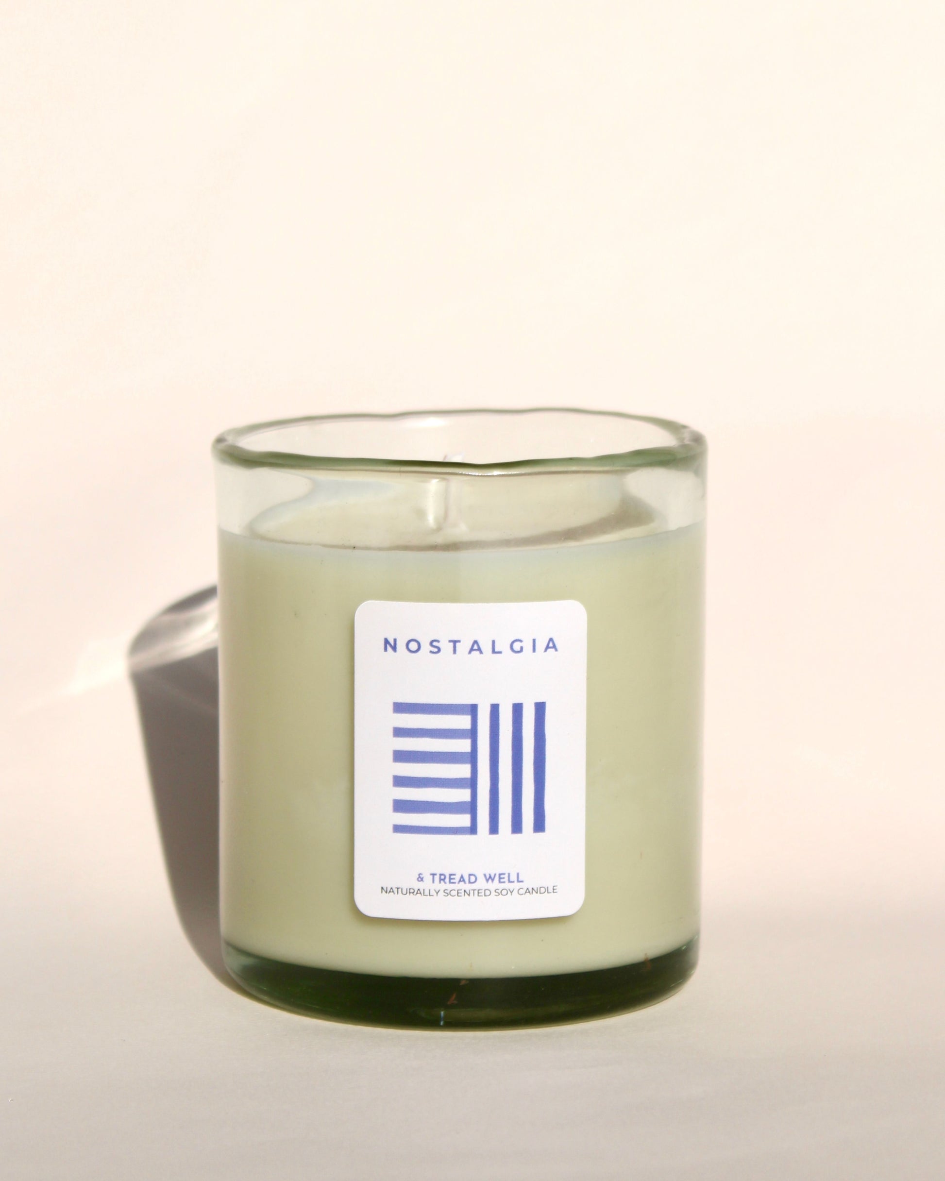 Person holding a candle with a brand label in a grassy field