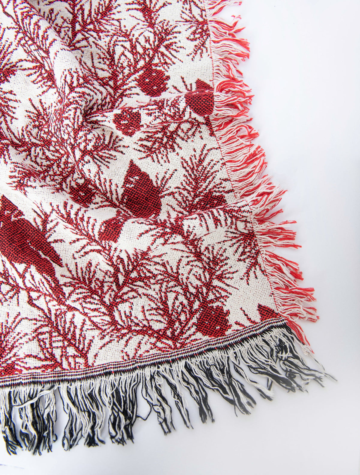 Close-up of Cherie Cranberry red cardinal, pine branch, and pinecone woven cotton throw with fringe