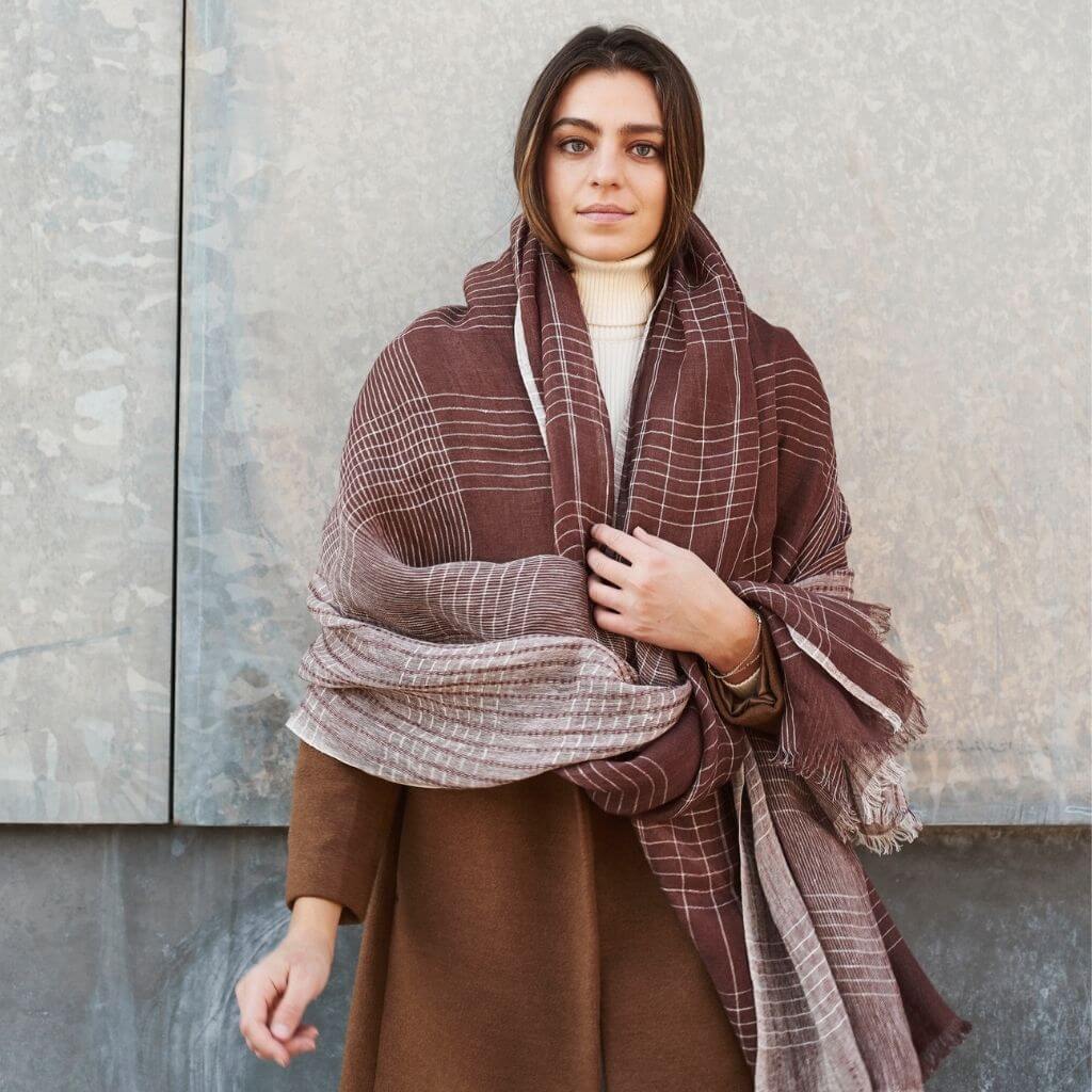 Auro Cinnabar Handwoven Earthy Rust Maroon Linen Scarf draped elegantly over a model against a textured wall.