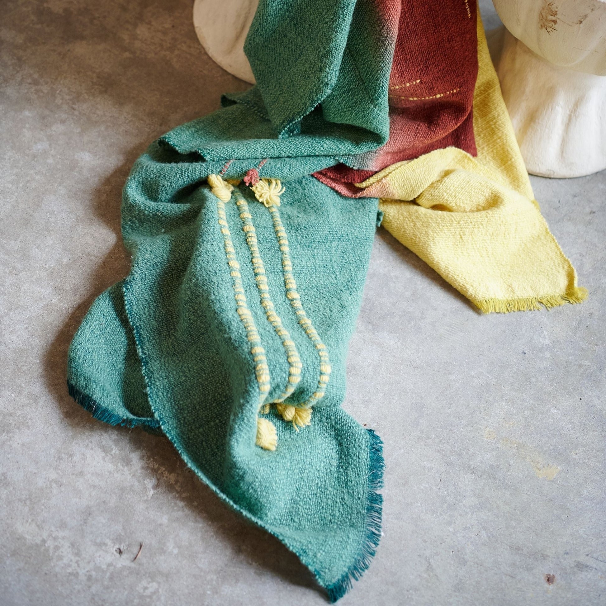 Avocado Green Multi Color Warm Hues Hand Woven Hand Knotted Textured Merino Throw draped over a surface.