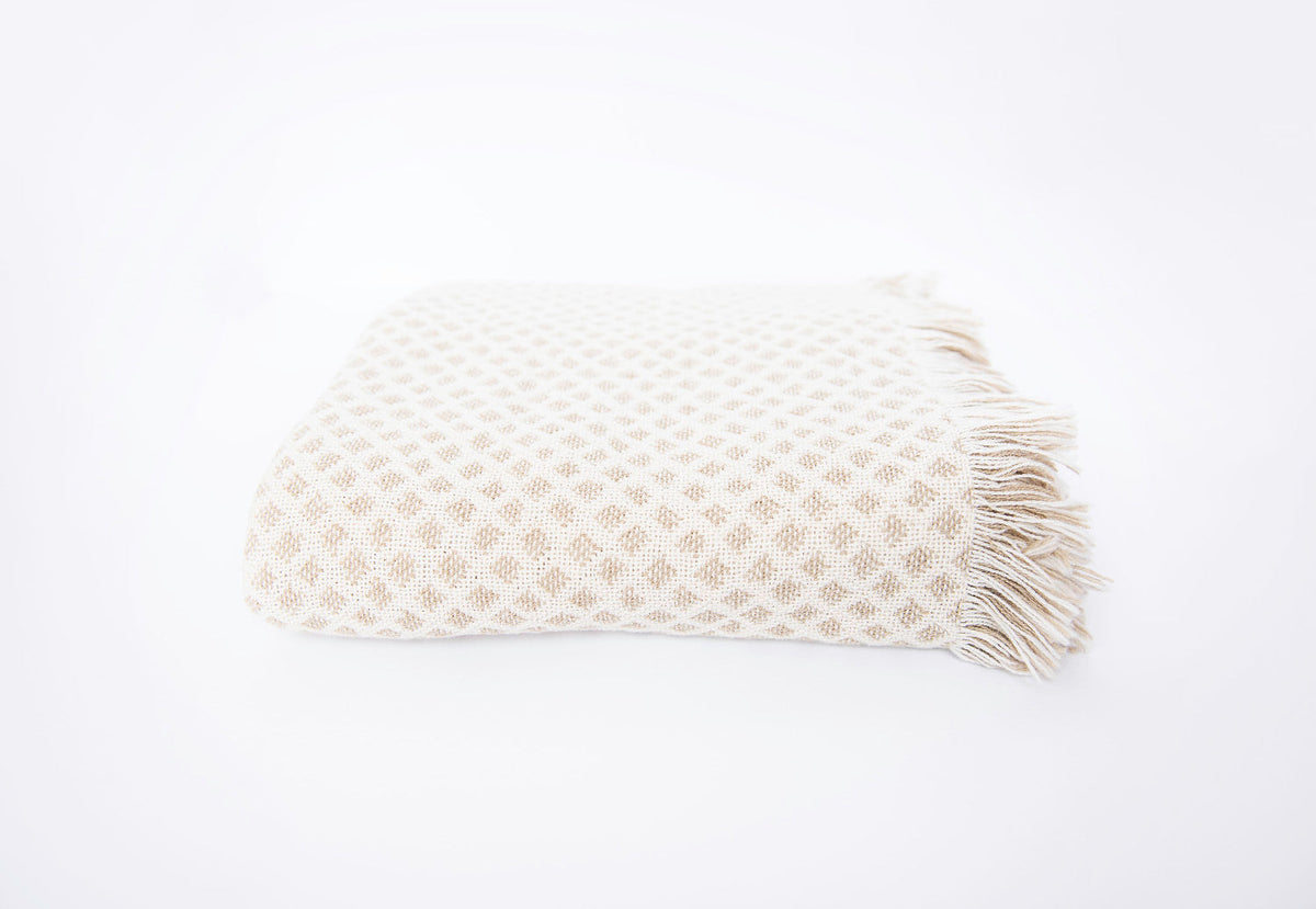 Front view of folded cream and beige diamond woven cotton throw on a white background