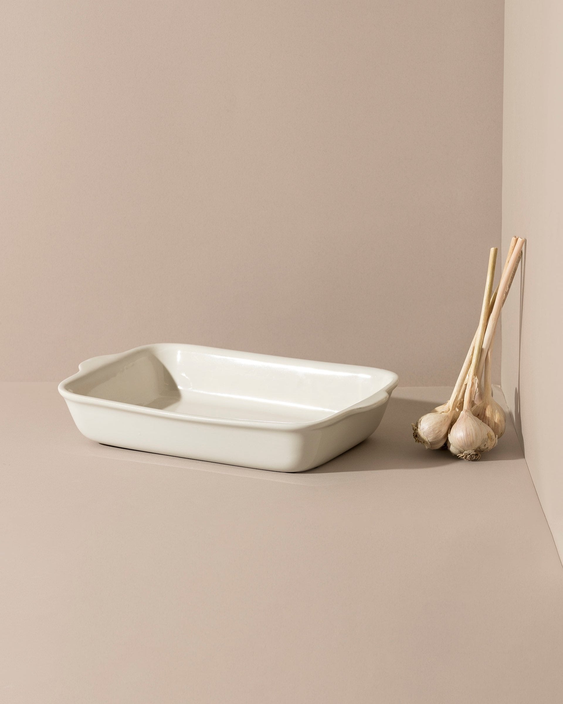 A stack of rectangular stoneware baking dishes in beige, blue, and green colors.