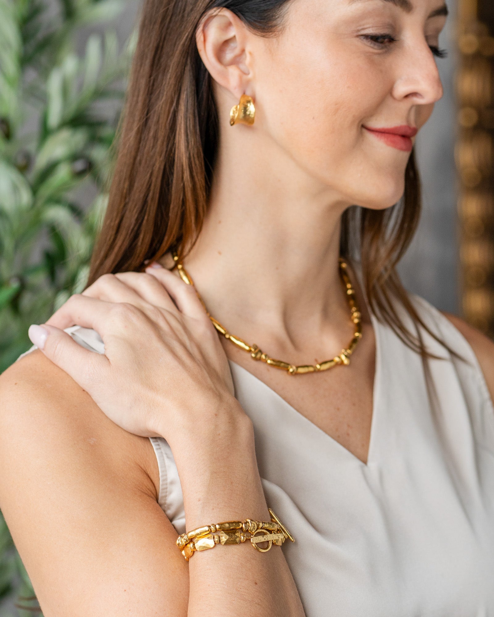Gold necklace with organic, elongated and irregular bead shapes spaced along a double strand chain, finished with an adjustable clasp.