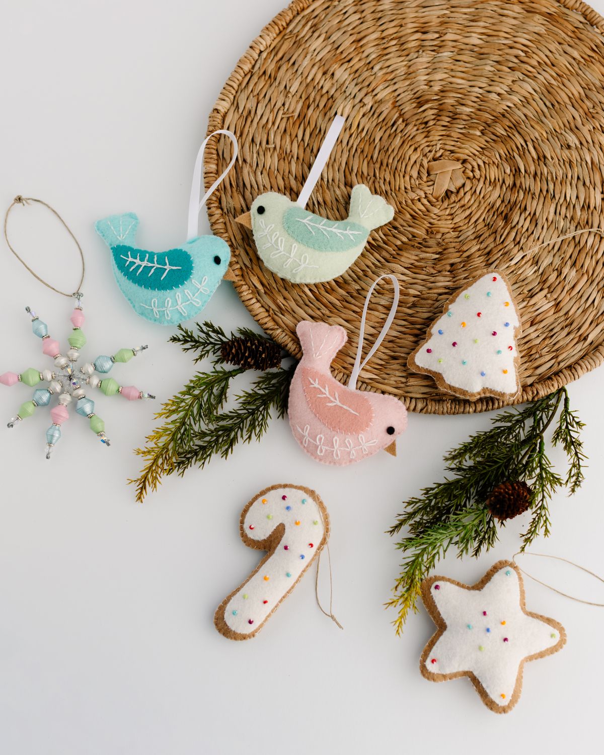 Decorative Christmas ornaments including birds and numbers on a woven mat with greenery.