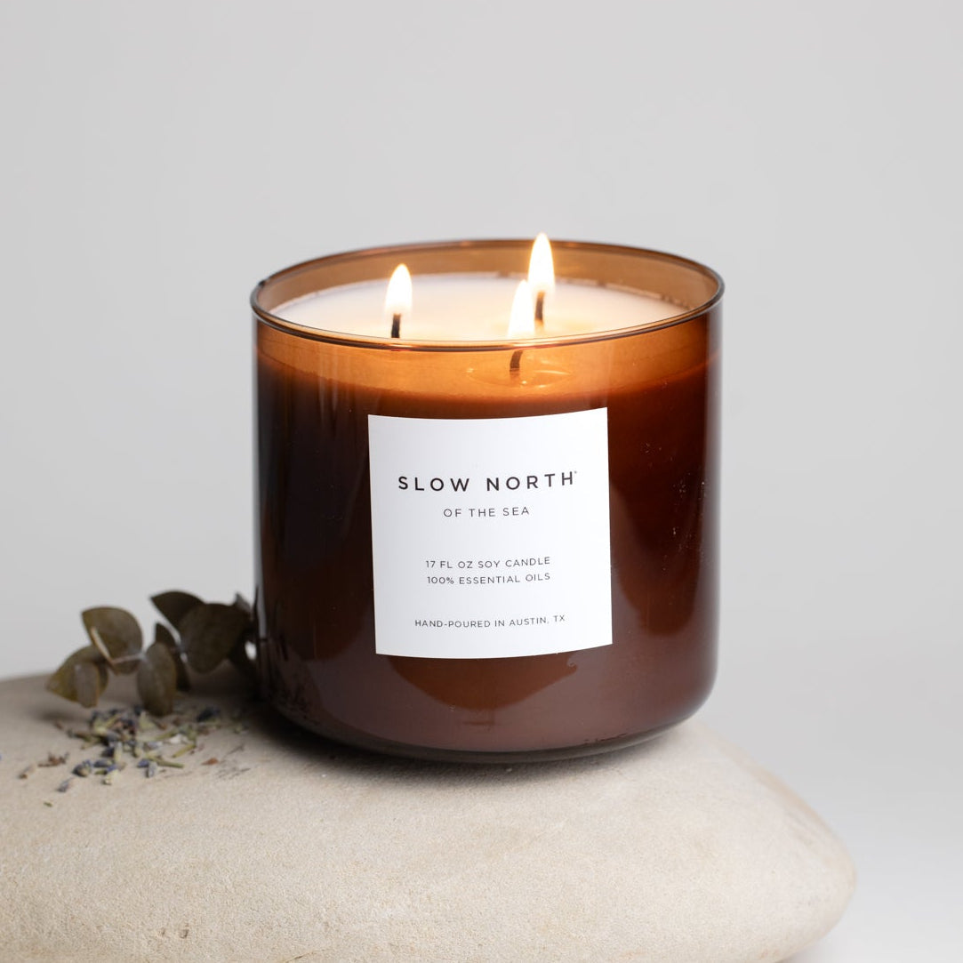 Candle with a label on a stone surface against a light background