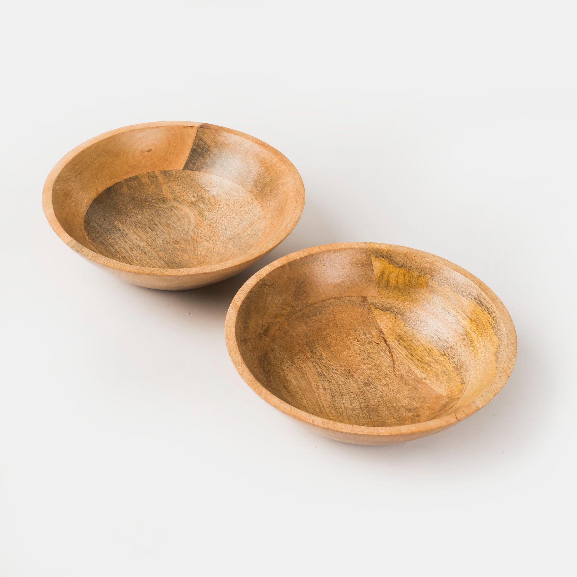 Overhead shot of a round mango wood serving bowl filled with fresh purple grapes.