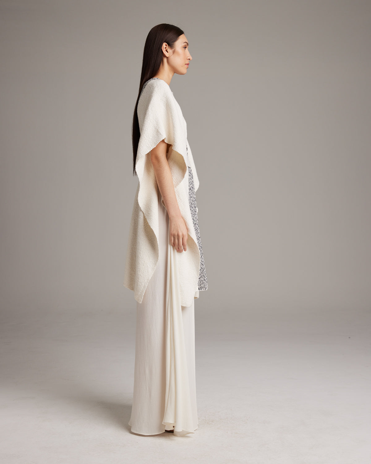 Model wearing a cream Estrella Kaftan, side view, showcasing its texture and flow.