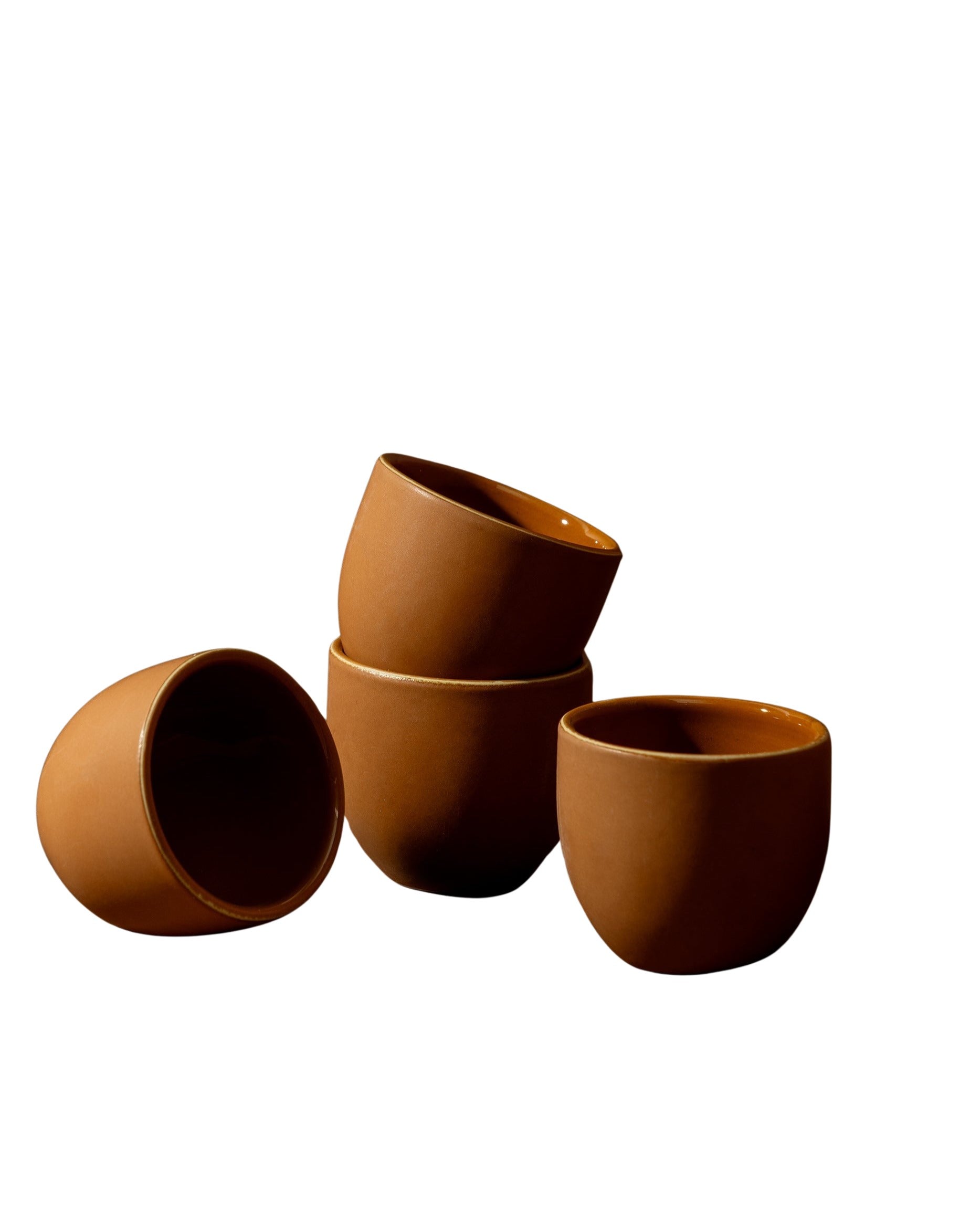 A set of three white stoneware coffee cups of varying sizes placed on a beige surface.