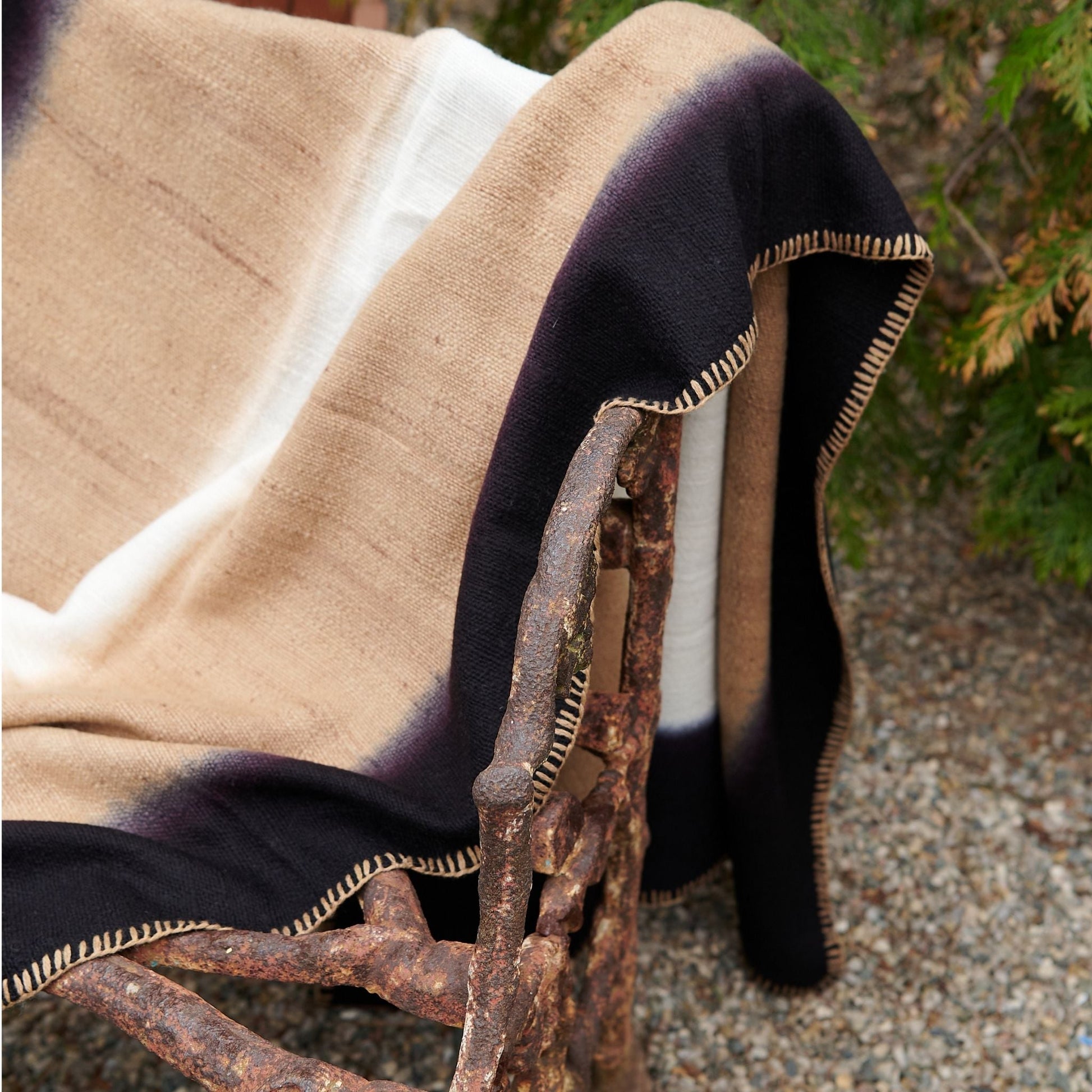 Siro Brown Handwoven Merino Artisan Throw Blanket draped over a rustic chair, highlighting the intricate stitching and rich colors.