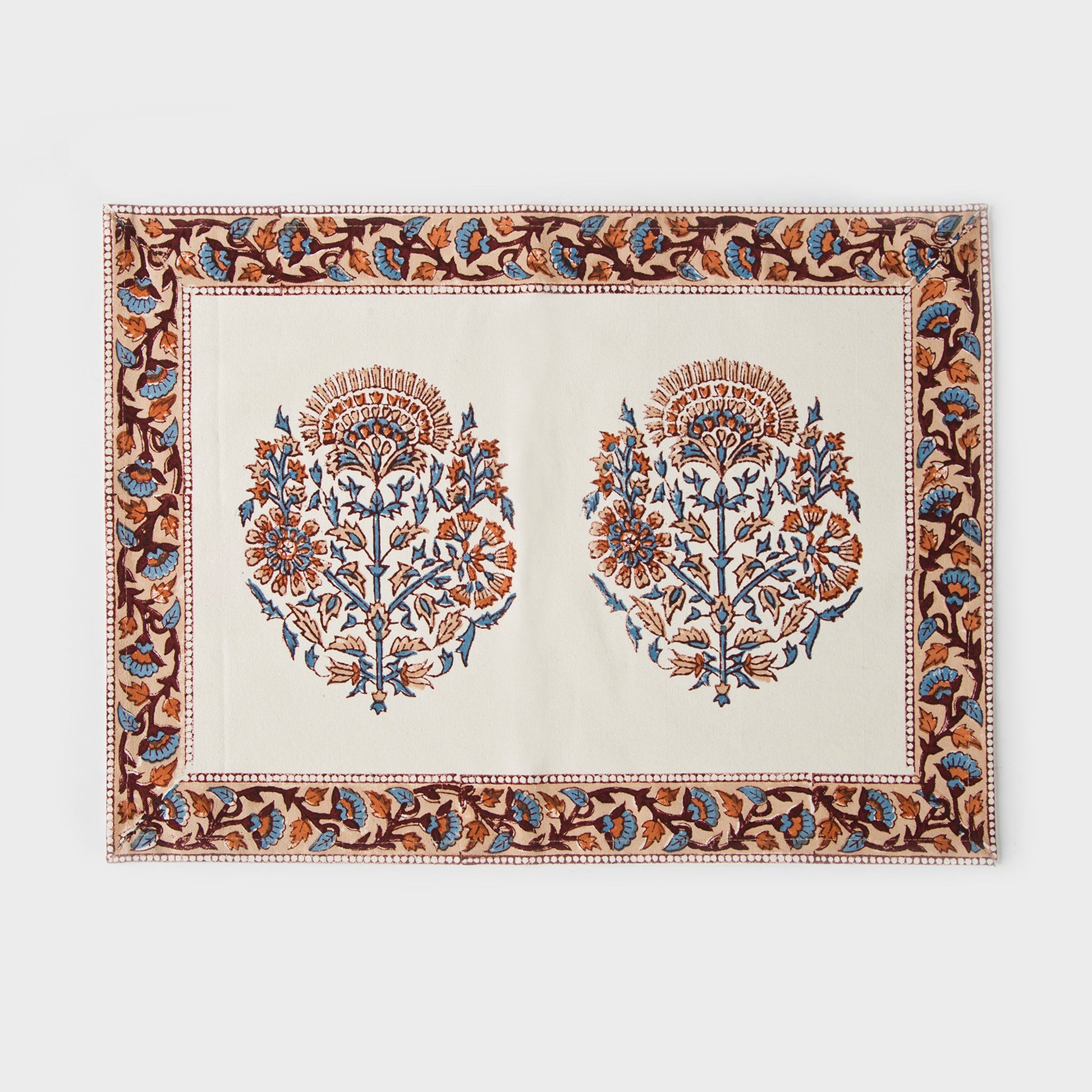 Close-up of pink and blue floral block print on white cotton placemat with decorative border.