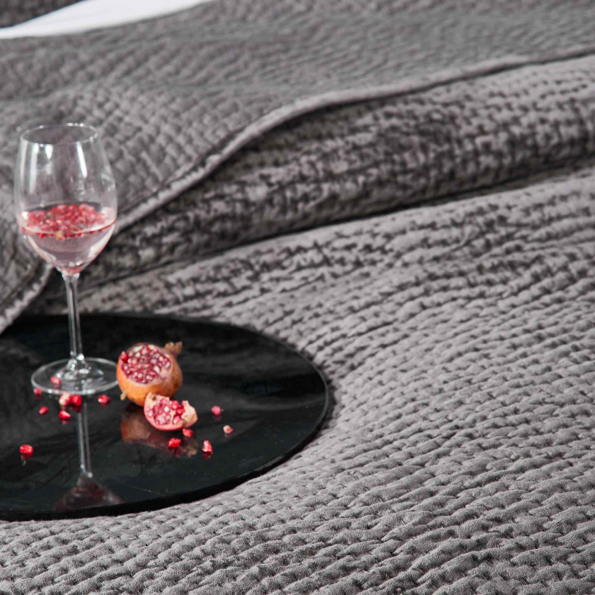 CL-184-9496-LOT1_4|Charcoal grey textured waffle weave coverlet with a glass of drink and pomegranate, creating a cozy ambiance.