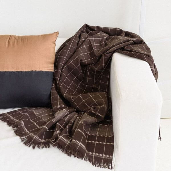 Treacle Checks Pattern Organic Cotton Handloom Throw draped over a couch with a decorative pillow.