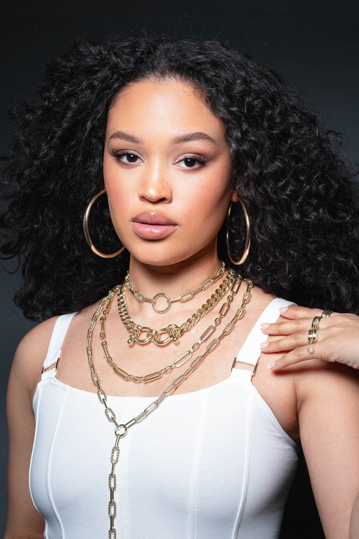 Woman wearing layered gold jewelry showcasing the Enzo Lariat Necklace