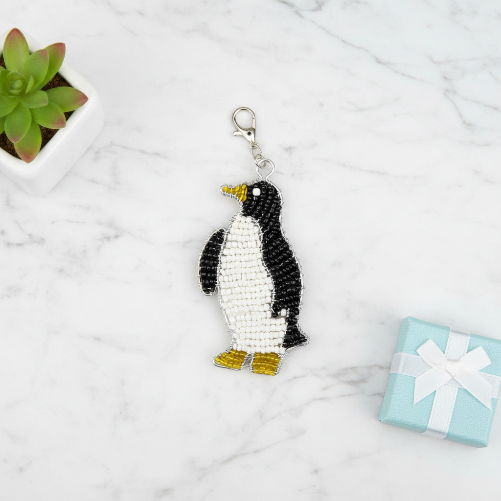 Penguin keyring flat lay on marble surface with succulent and gift box