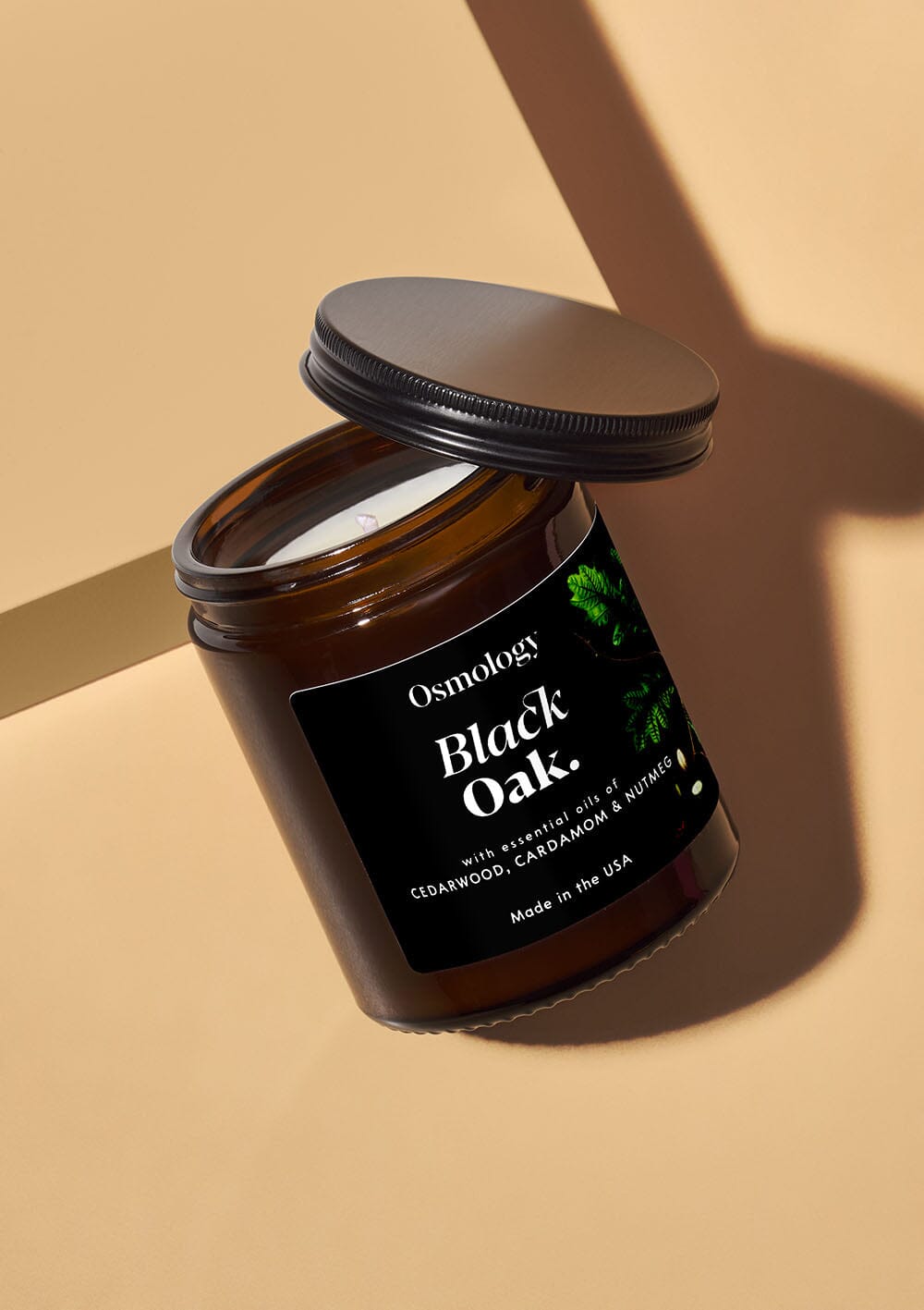 Osmology Black Oak scented candle, brown glass jar with black label and black lid on white background