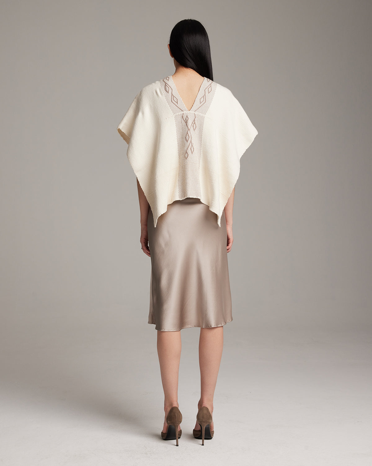 Back view of a model wearing a cream-colored Copihue Manta with geometric embroidery