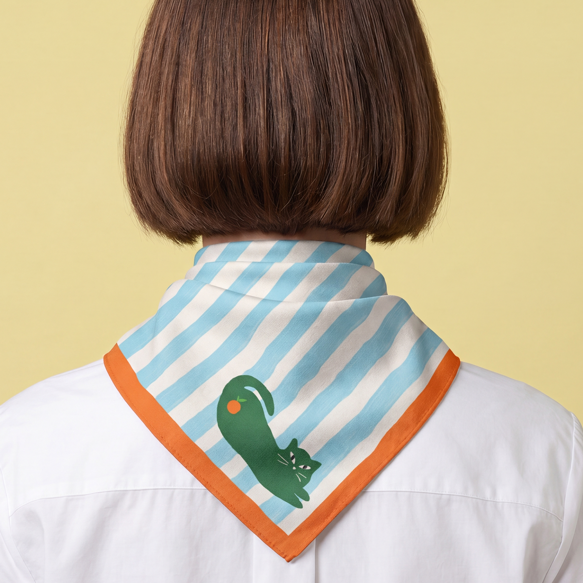 woman wearing a cyan blue striped bandana with a green cat design, with orange color border and an orange fruit on a yellow background