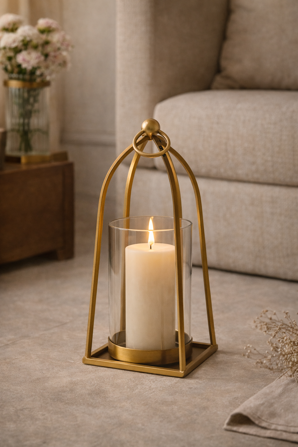 Gold lantern with a candle on a wooden floor in a living room setting
