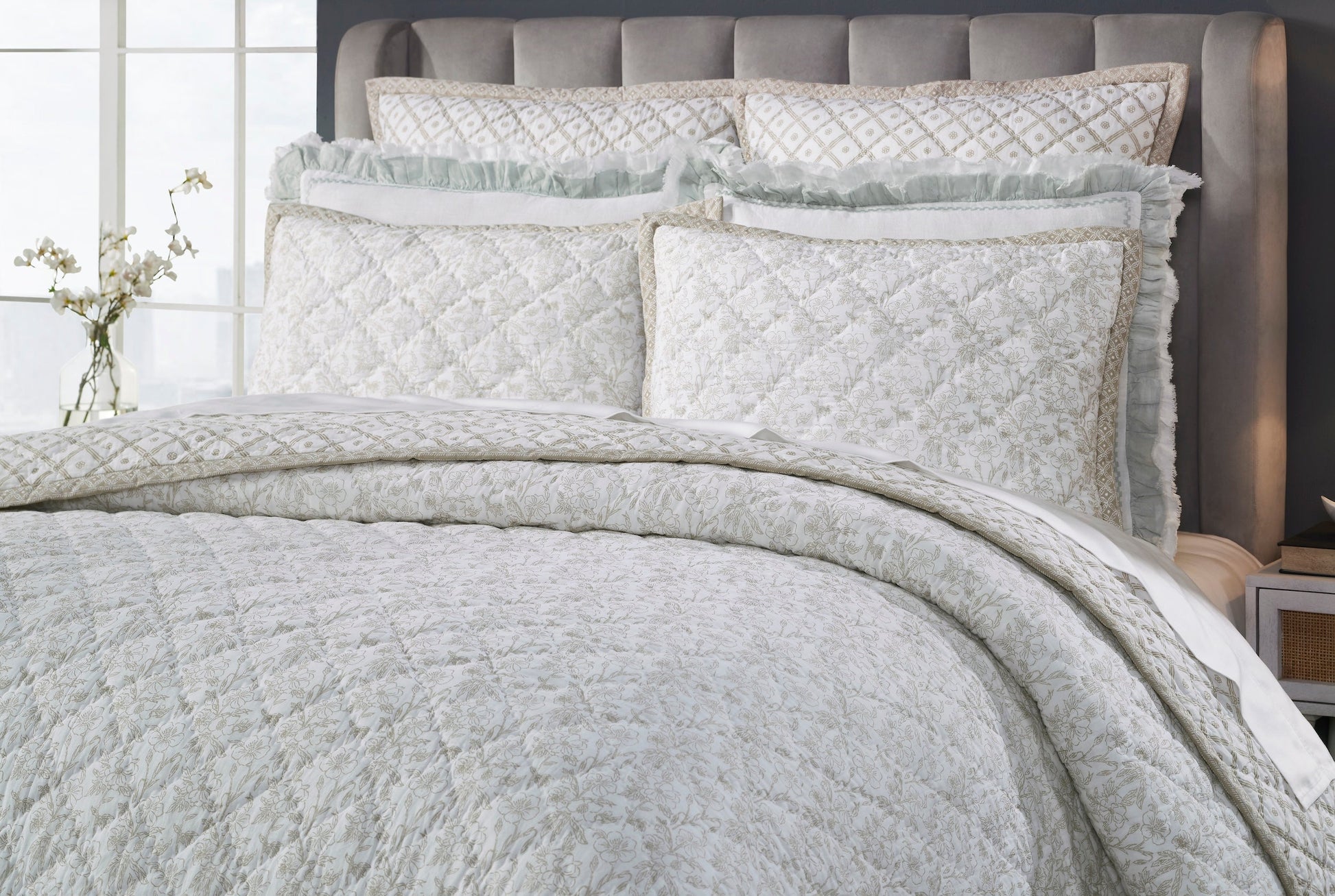 QT-346-11096_3|Close-up of natural beige floral quilt and decorative shams on bed. Intricate quilting detail & reversible border. Luxury bedding.