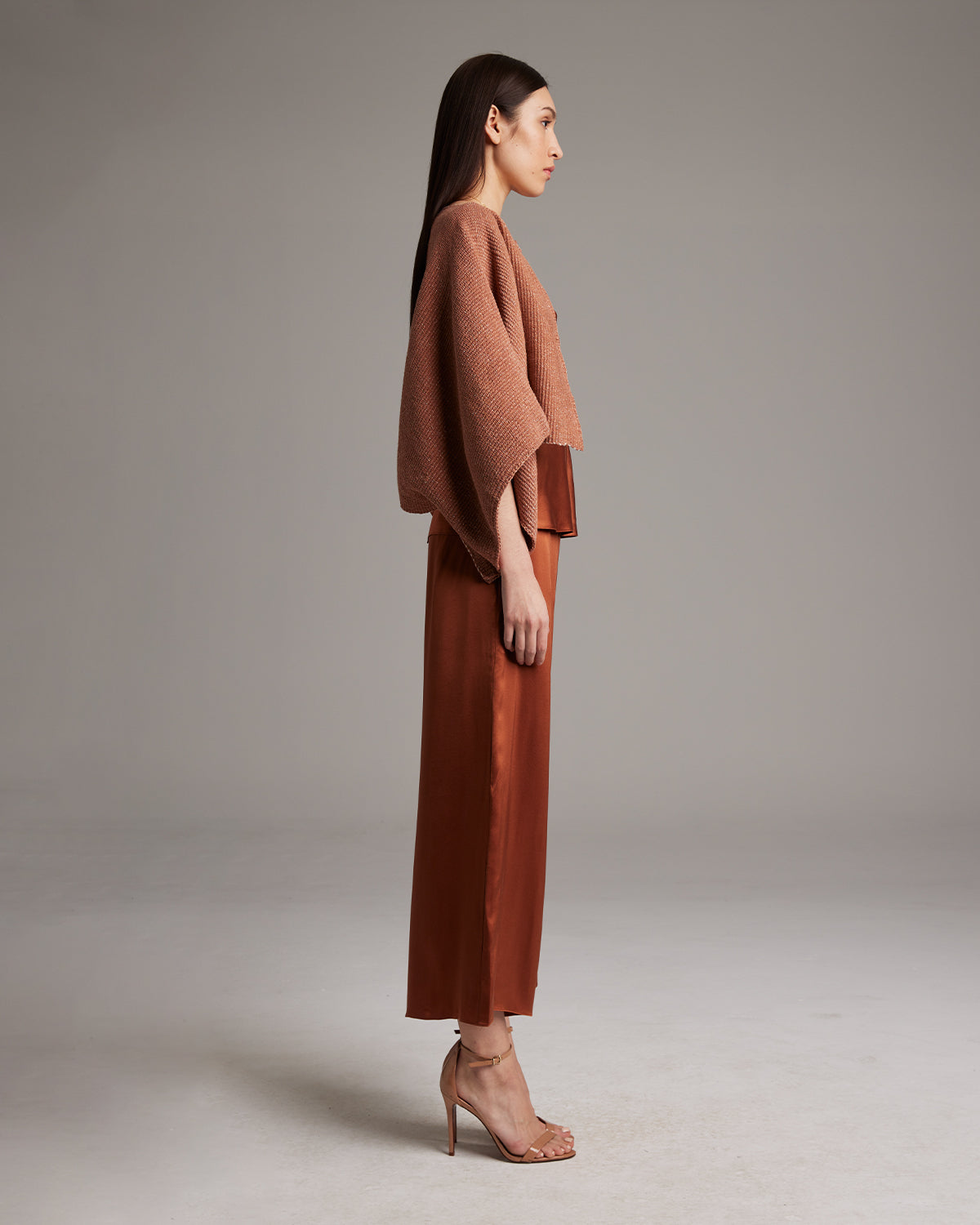 Model wearing a shimmering cotton bolero in copper color, paired with a rust pantsuit.