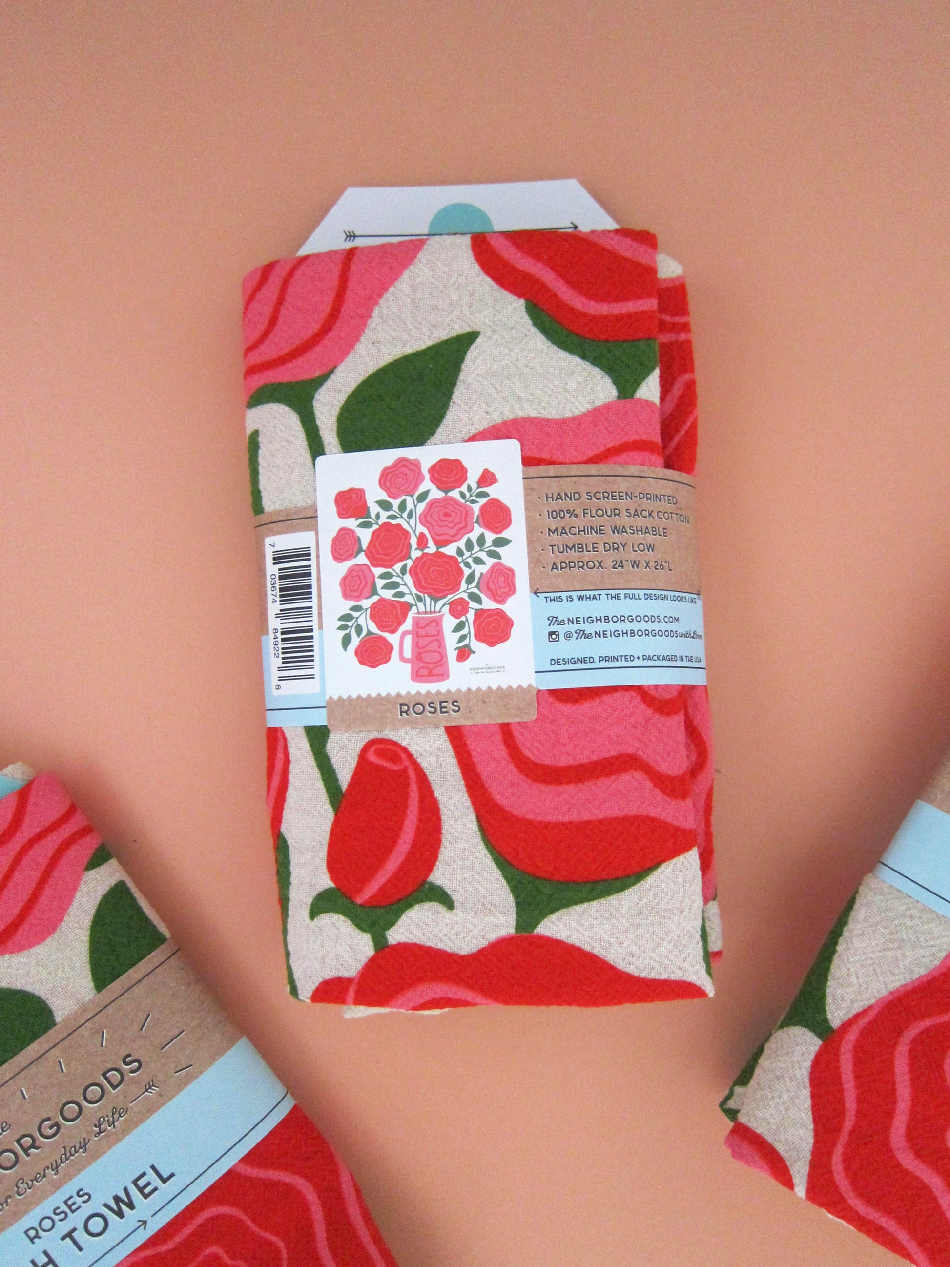 Back view of The Neighborgoods Roses dish towel in a ready-to-gift sleeve, showcasing product specifications and an image of the full tea towel.