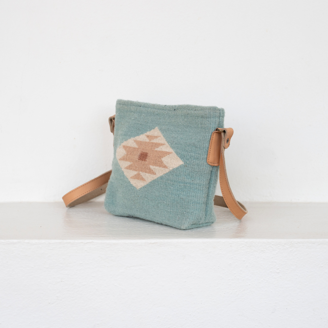 Handwoven crossbody bag with minimalist Zapotec butterfly design in soft blue tones; features adjustable leather strap and two internal pockets for daily essentials