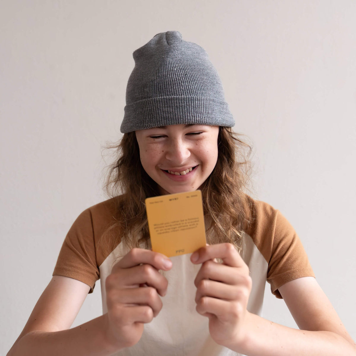 person wearing a beanie playing a would you rather card game and smiling