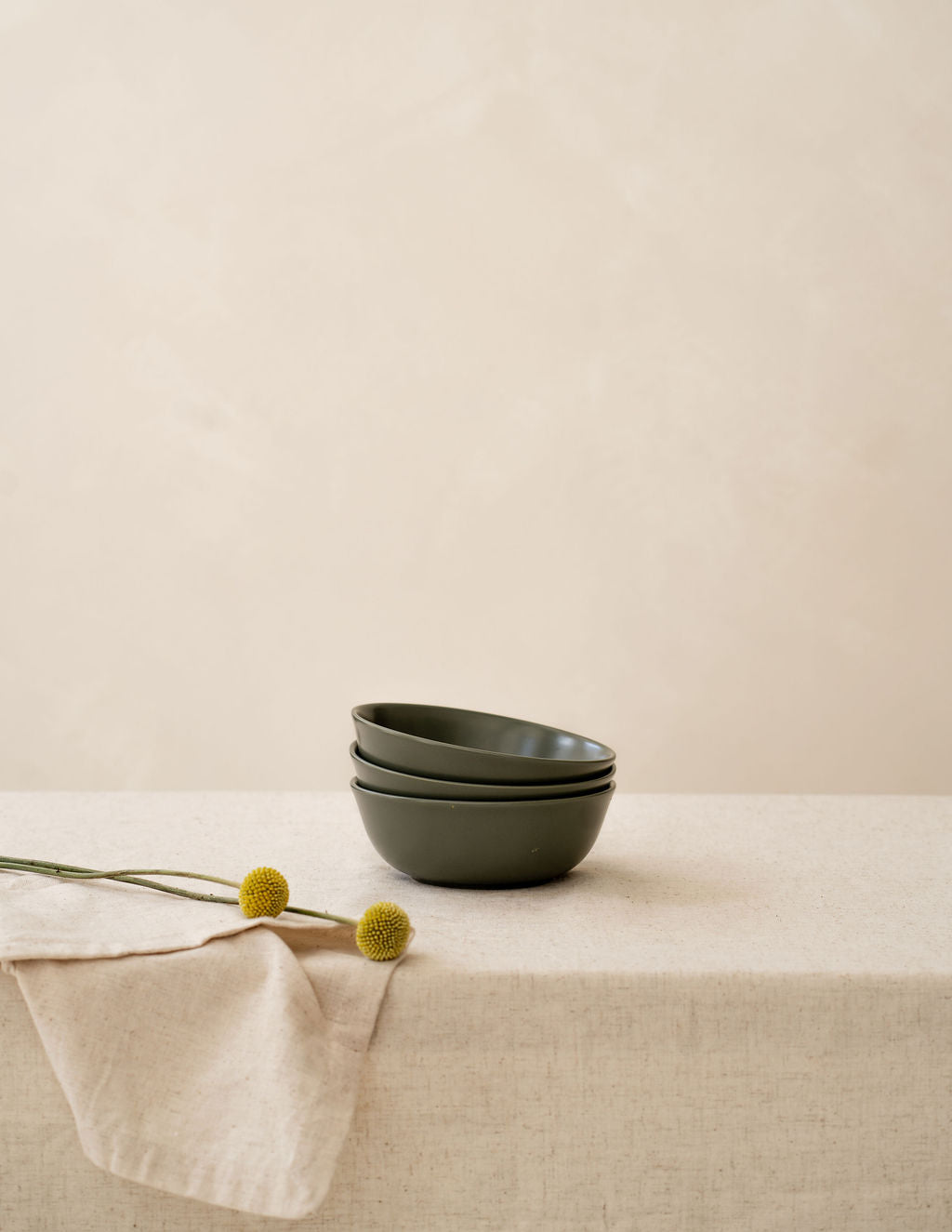 Stack of Moss green non-toxic ceramic bowls from Hamkke Home on a neutral tablecloth for product display.