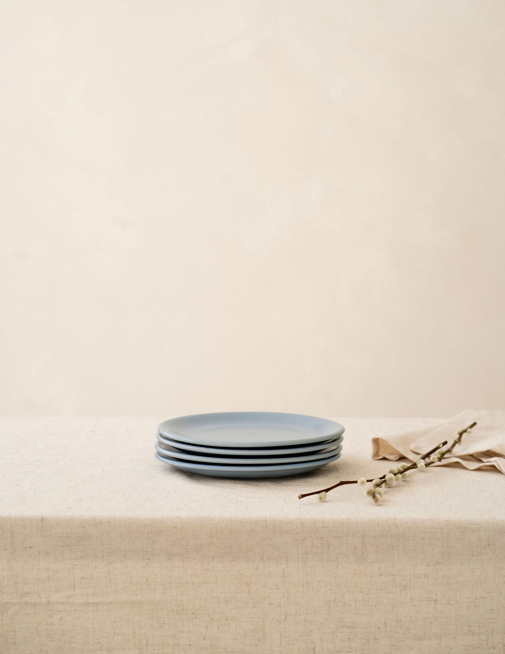 A set of Wave blue ceramic side plates stacked on top of each other on a beige linen tablecloth.