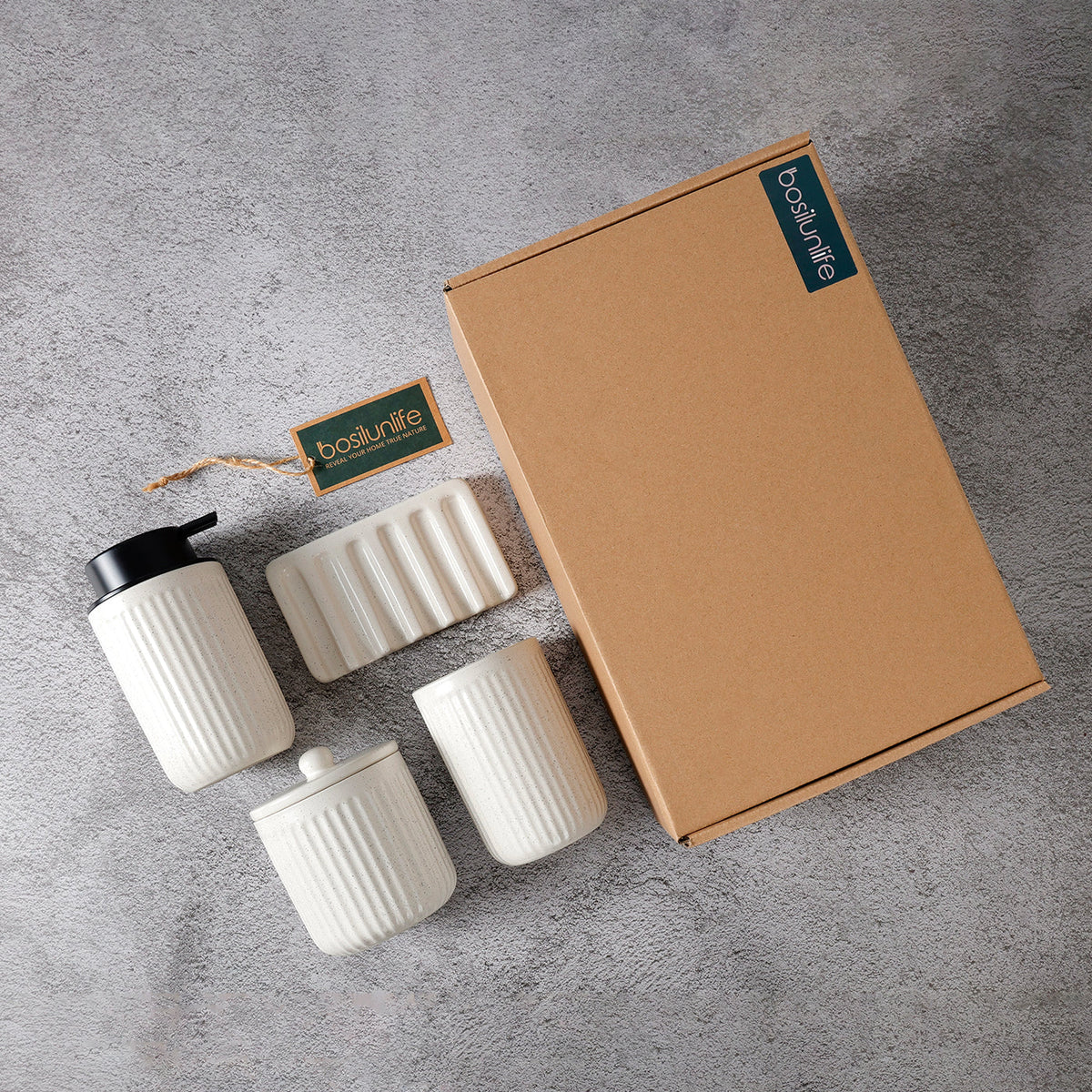 Flat-lay shot of the 4-piece BosilunLife bathroom organisation set in a speckled 'Pockmark Cream' finish, presented with its eco-friendly gift packaging. The set, crafted from GRS-certified recycled ceramic eco-clay, includes a fluted liquid soap dispenser with a black pump, a ribbed tumbler, a lidded storage jar, and a wavy-ridged soap dish.