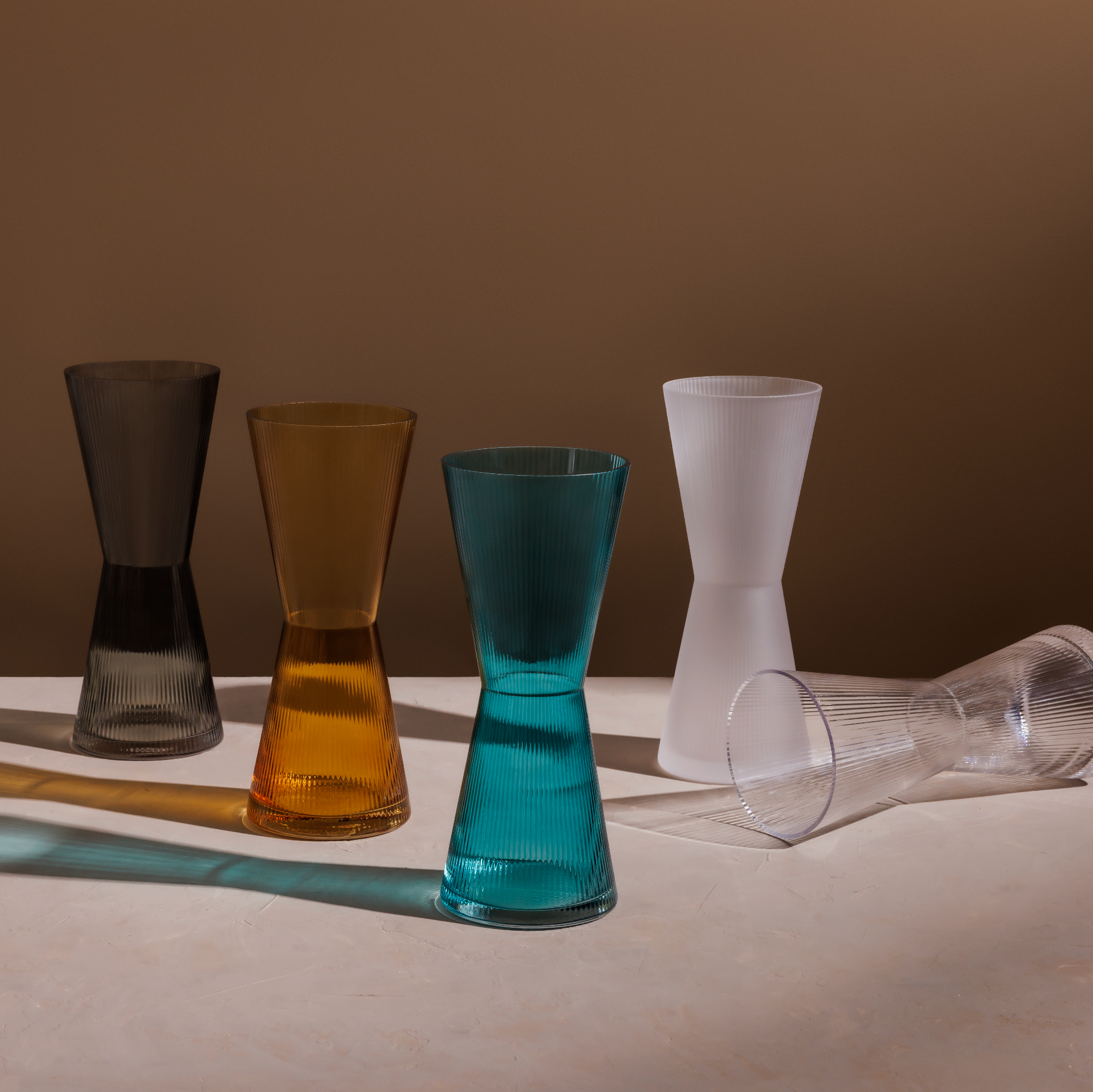 Set of colorful glass tumblers on a neutral background