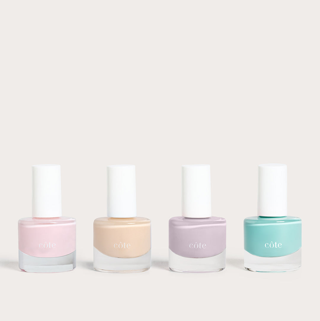 Côte Beauty Summer Vows Set, four nail polish bottles in blush pink, nude beige, soft violet grey and fresh aqua blue on a neutral background.