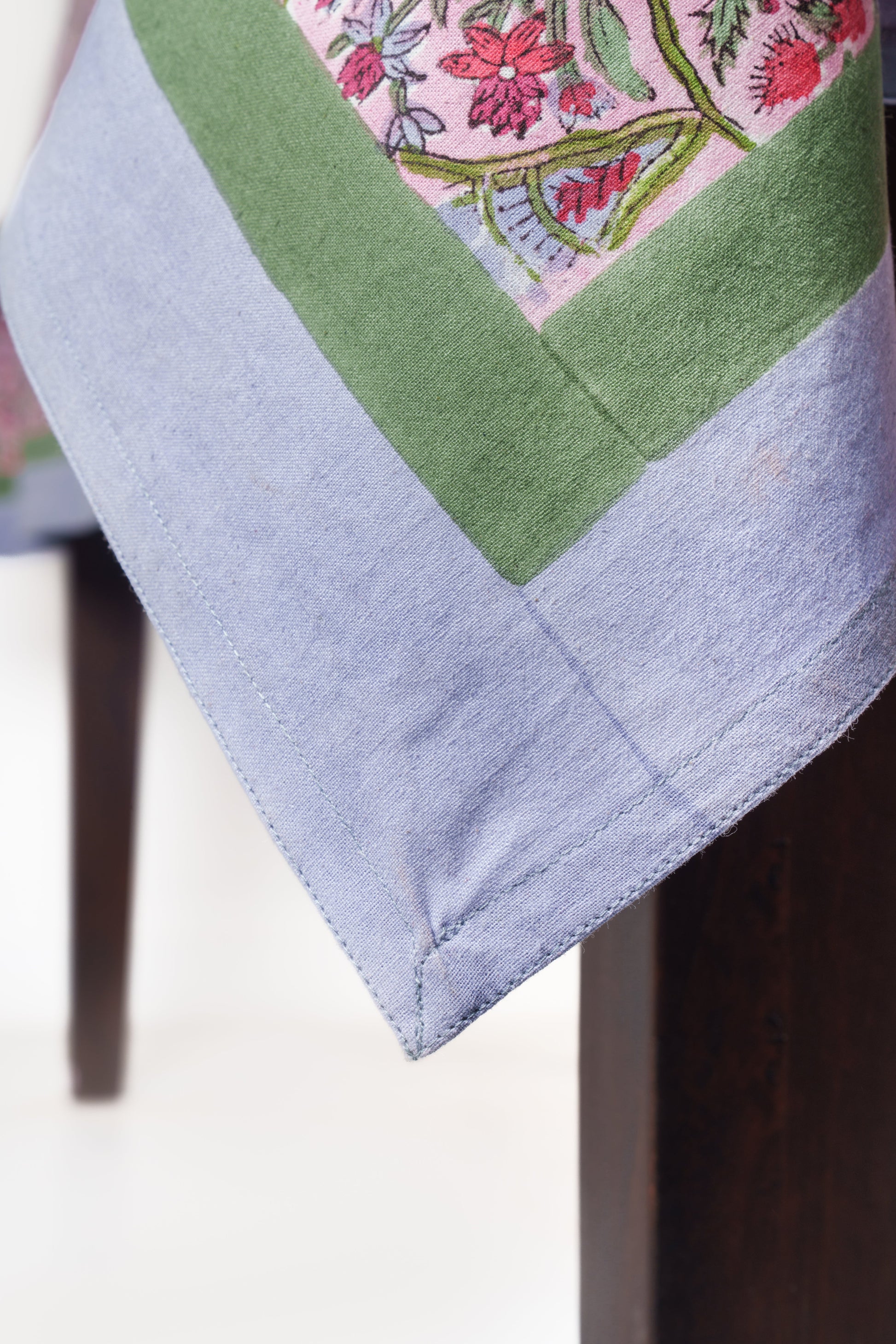 Pink arch blockprint tablecloth corner showing green border and lavender trim