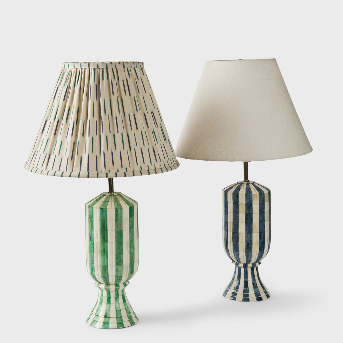 The Linea Duo lamp shades displayed on green glass table lamp bases in a bright room.