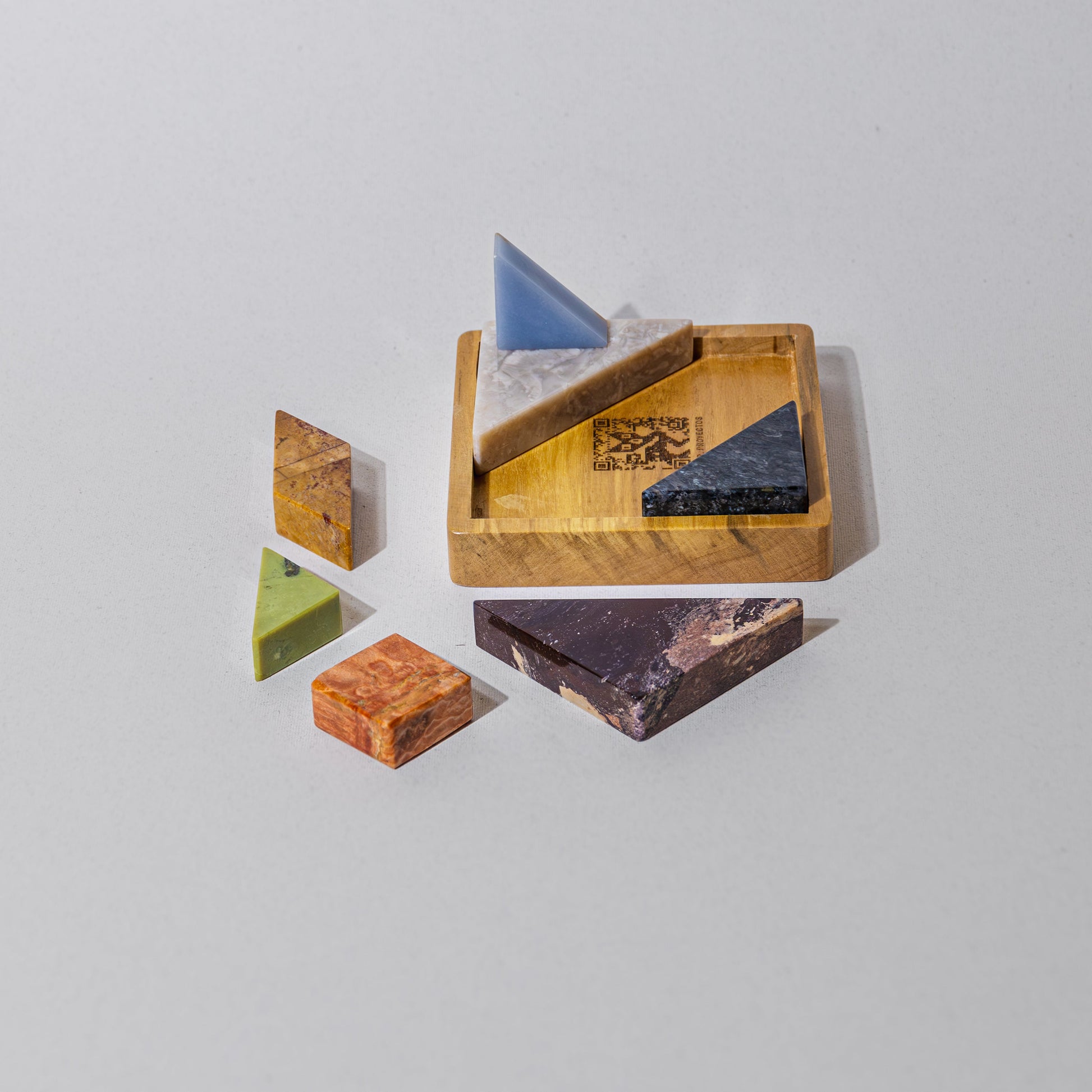 Close-up view of the solid Tangram stone pieces showcasing their smooth polished finish on a white background.