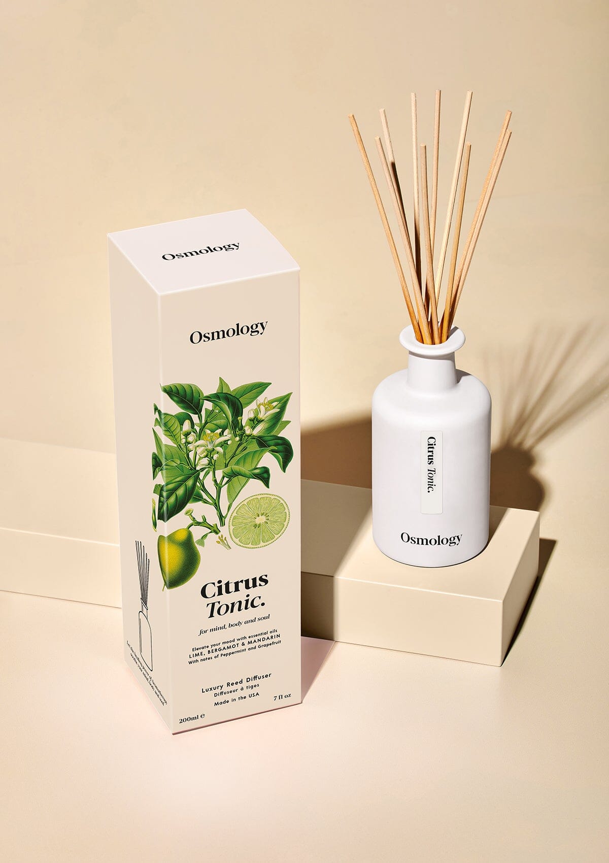 Osmology citrus reed diffuser next to decorative product packaging in a white background