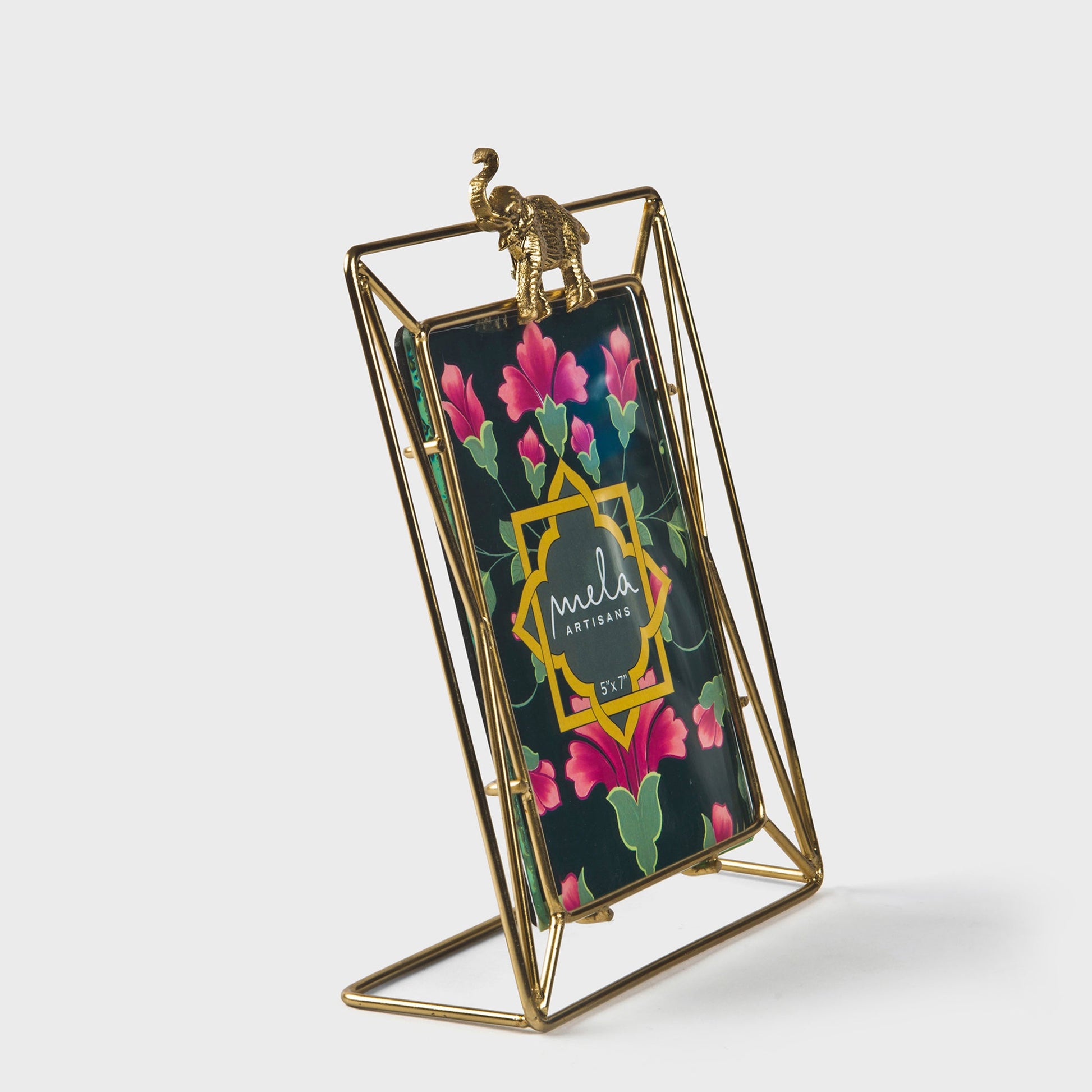 Ornate gold elephant frame holding a vibrant floral print on a wooden console.
