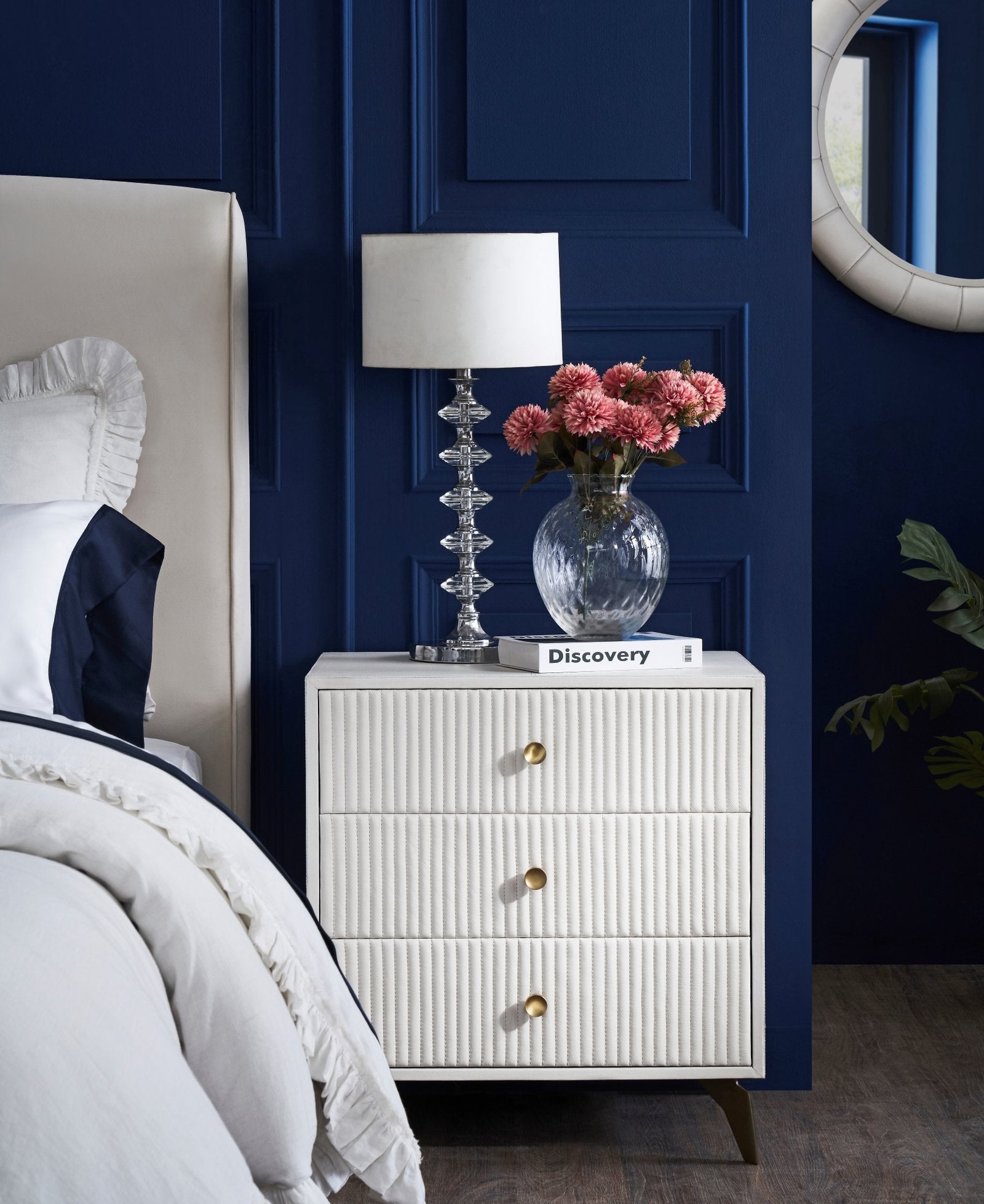FN-5202-X-1_1|Elegant white ribbed bedside chest with gold drawer pulls, crystal lamp, and pink flowers in a luxurious blue bedroom.