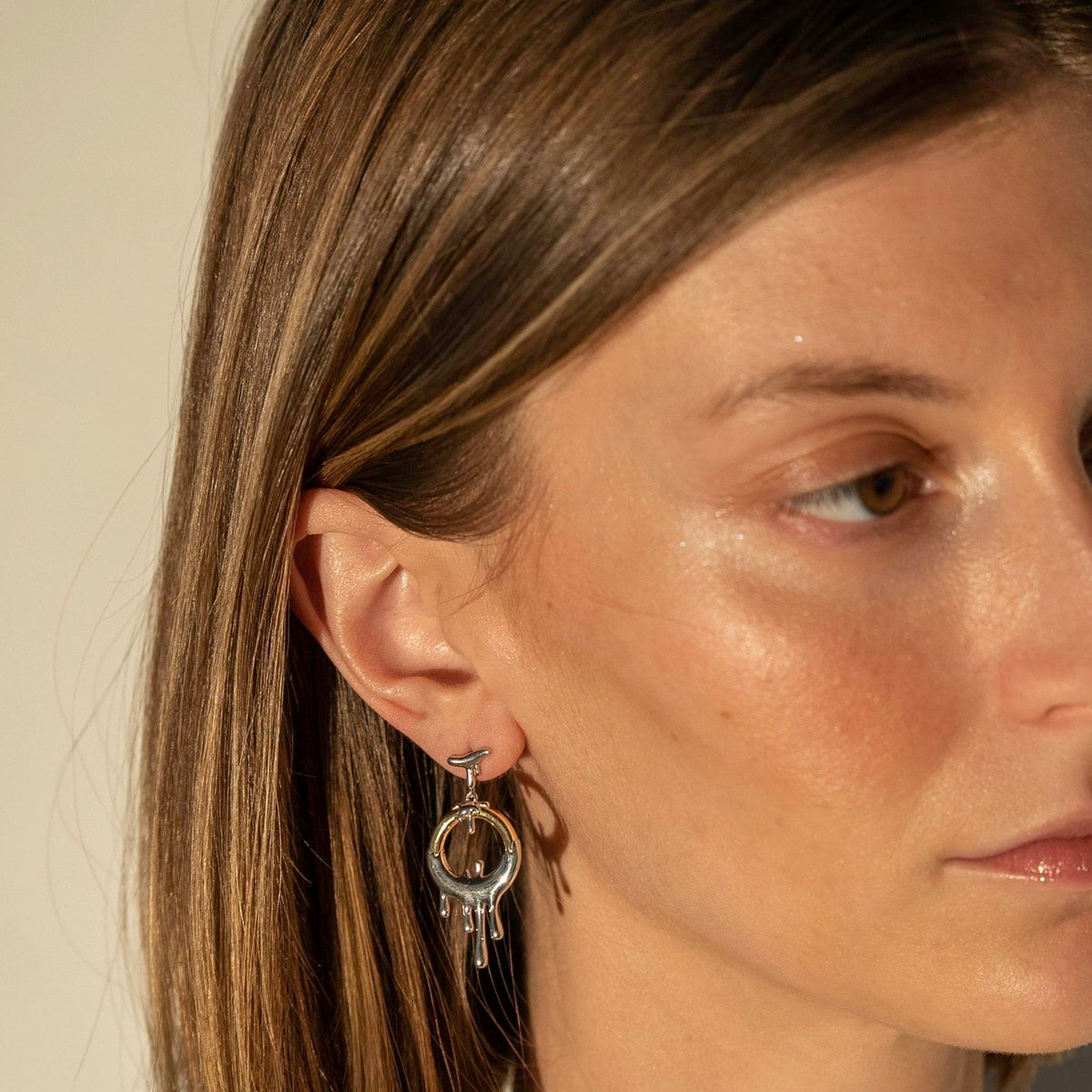 This image features the Equinox Earrings, elegant jewelry pieces that capture light and movement effectively. The earrings are designed with multiple circular elements, each connected to form a cascading chain.