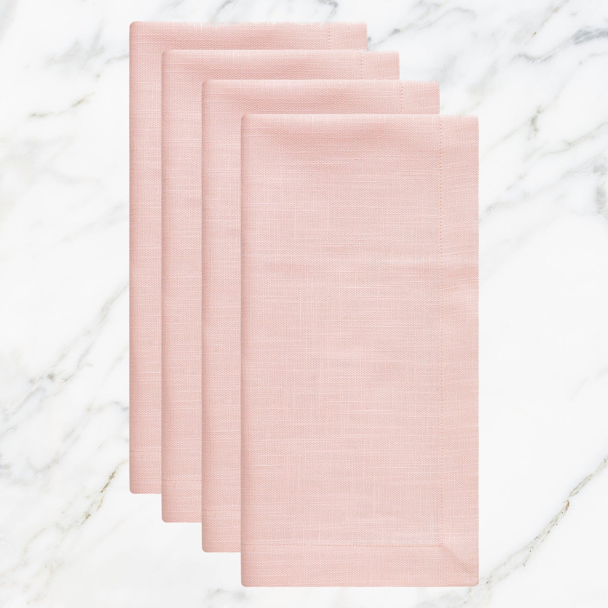 NP-4810-2020_1|Set of four elegant blush pink linen-look fabric dinner napkins, folded on a white marble surface.