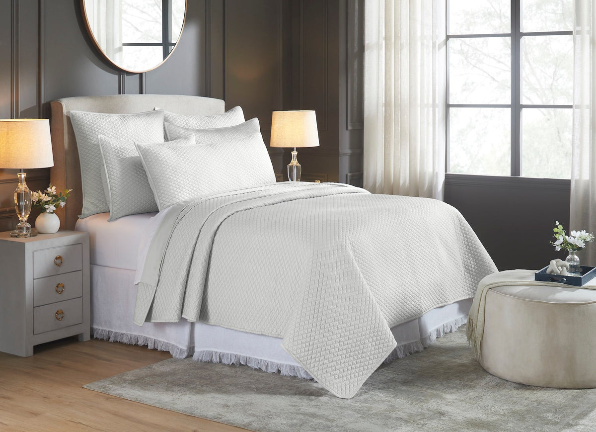 CL-266-9496_2|Soft white diamond quilted coverlet and matching pillows draped over a bed, enhancing the elegant bedroom decor.