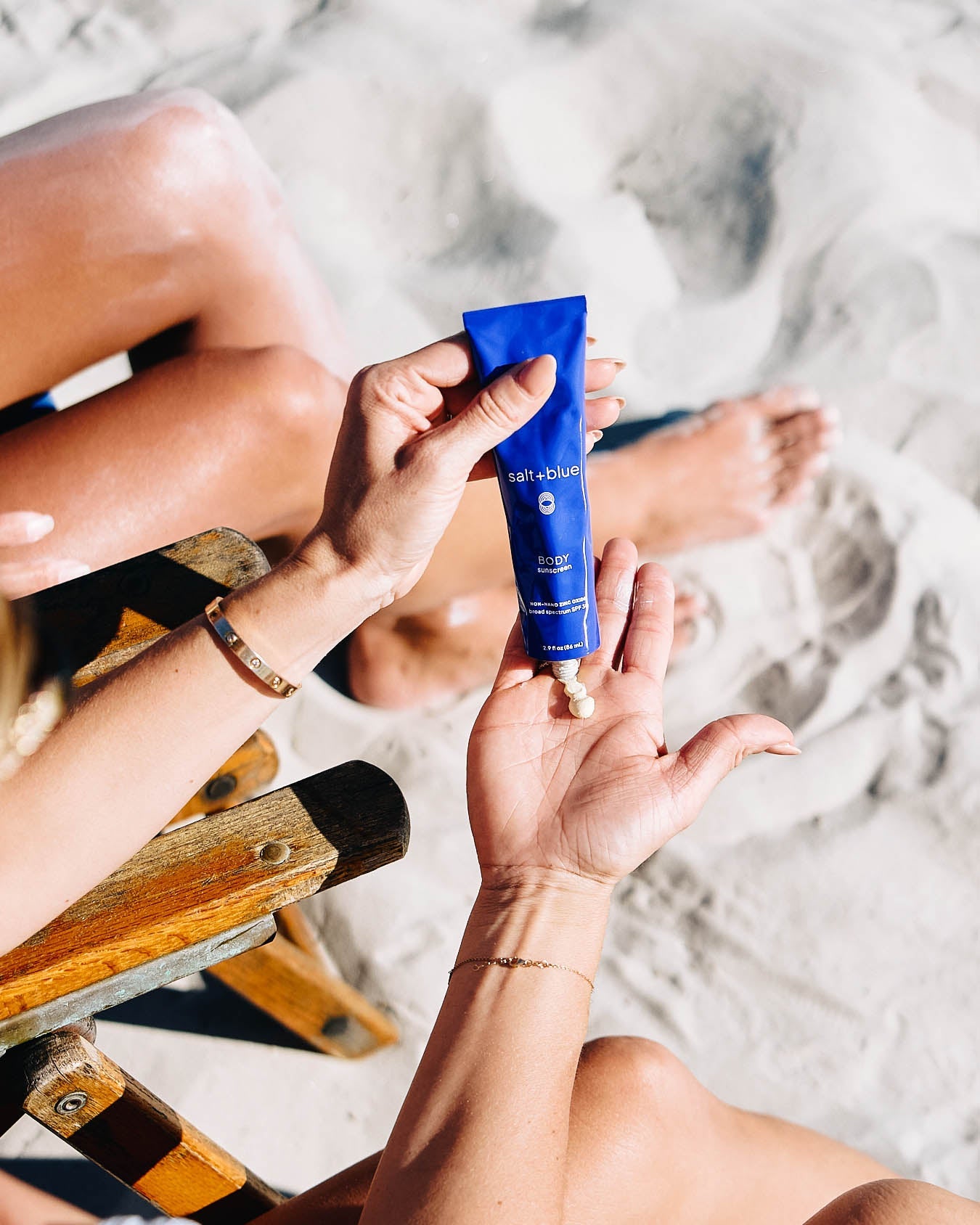 Person applying sunscreen to their hand on a beach