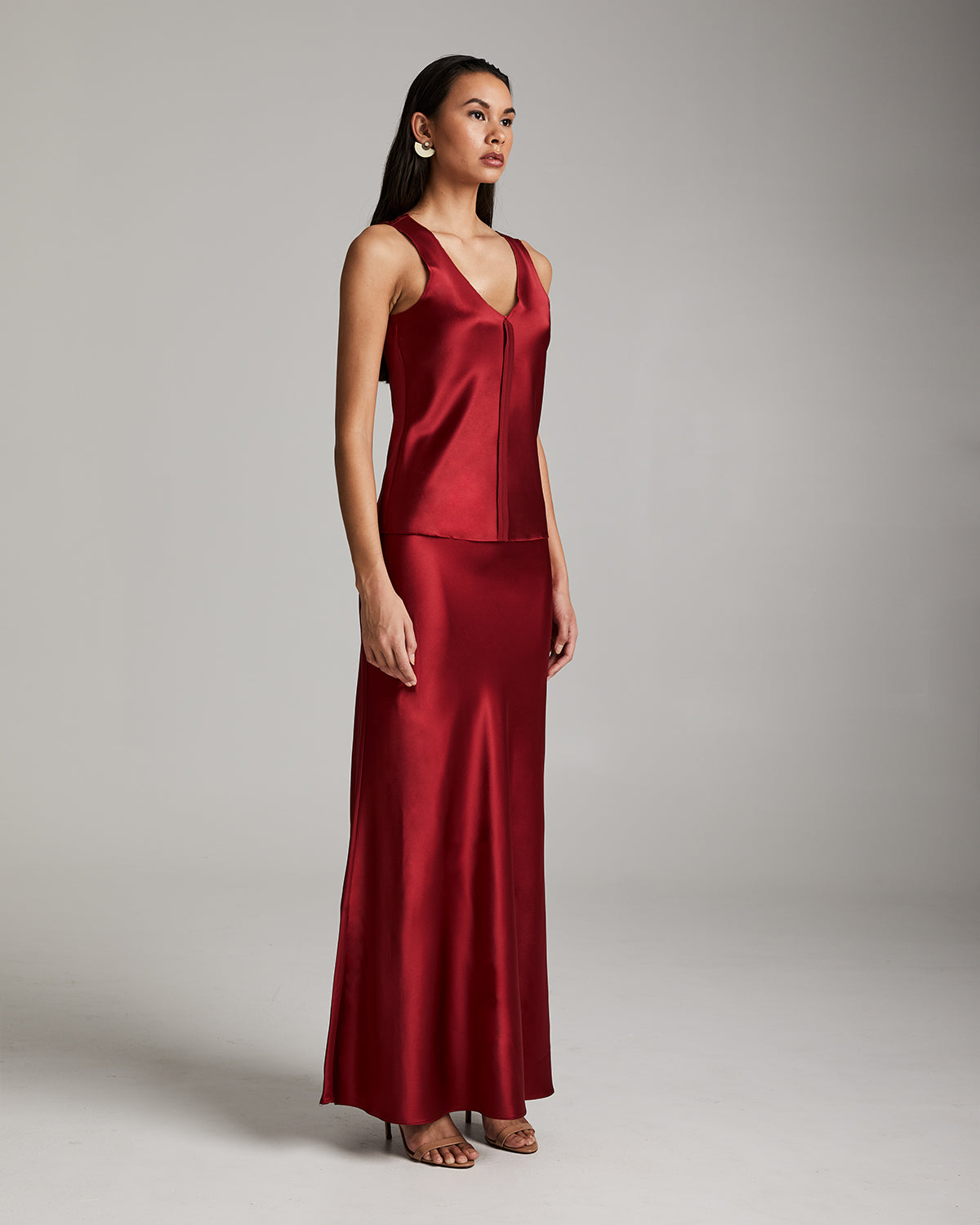 Model wearing a red silk Raw Edge Tank and matching skirt