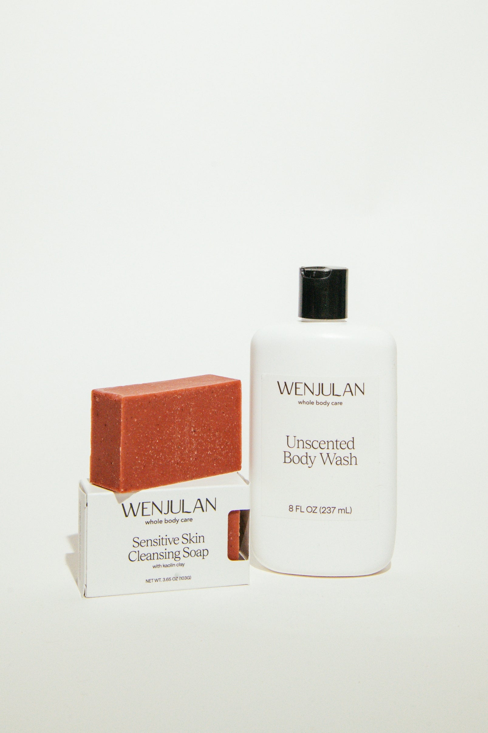 Wenjulan Whole Body Care Sensitive Skin Duo featuring the Wenjulan Sensitive Skin Cleansing Soap with Kaolin Clay bar and Wenjulan Unscented Body Wash liquid soap on a light gray background