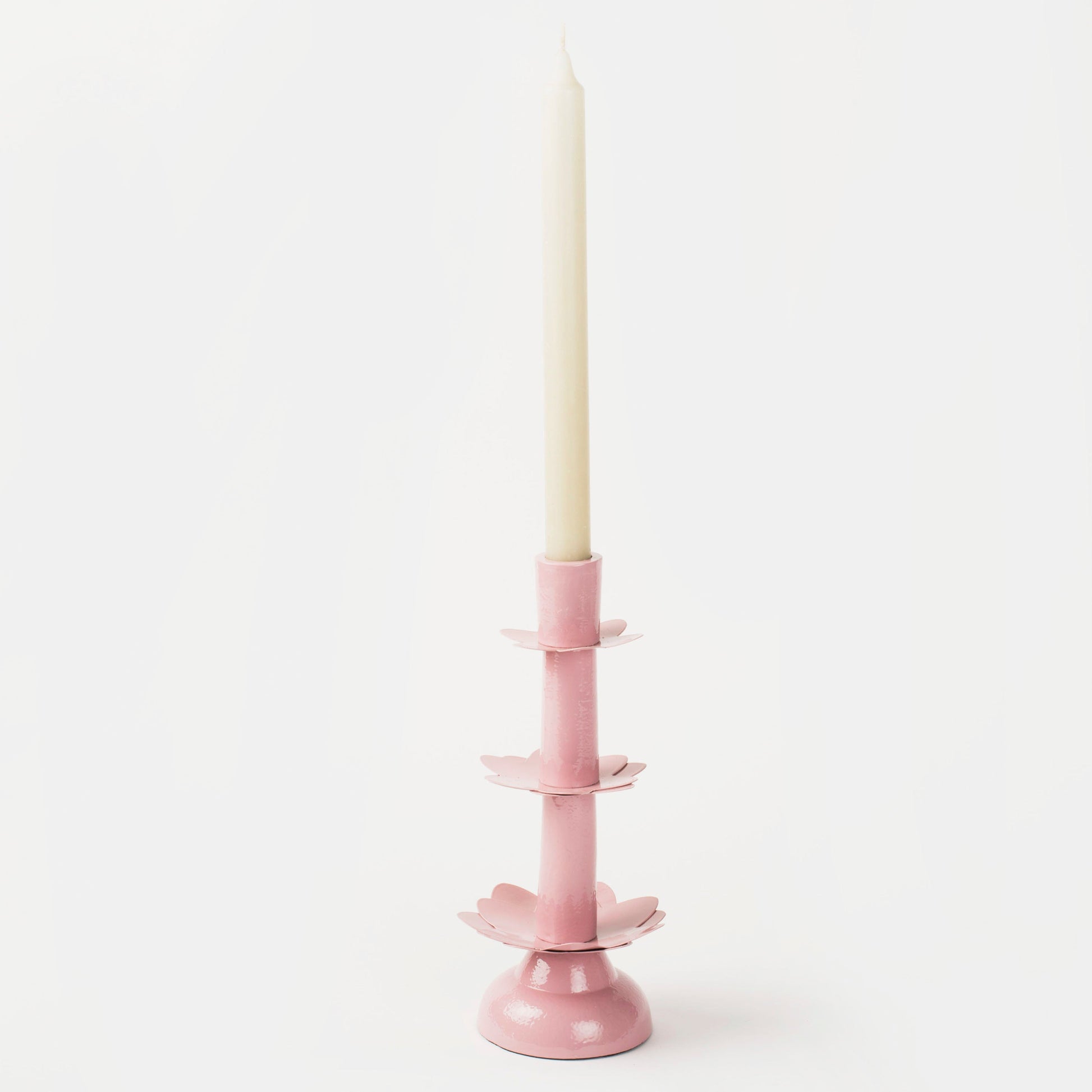 Sculptural pink aluminum taper candlestick with decorative tiered petals and a stable base.