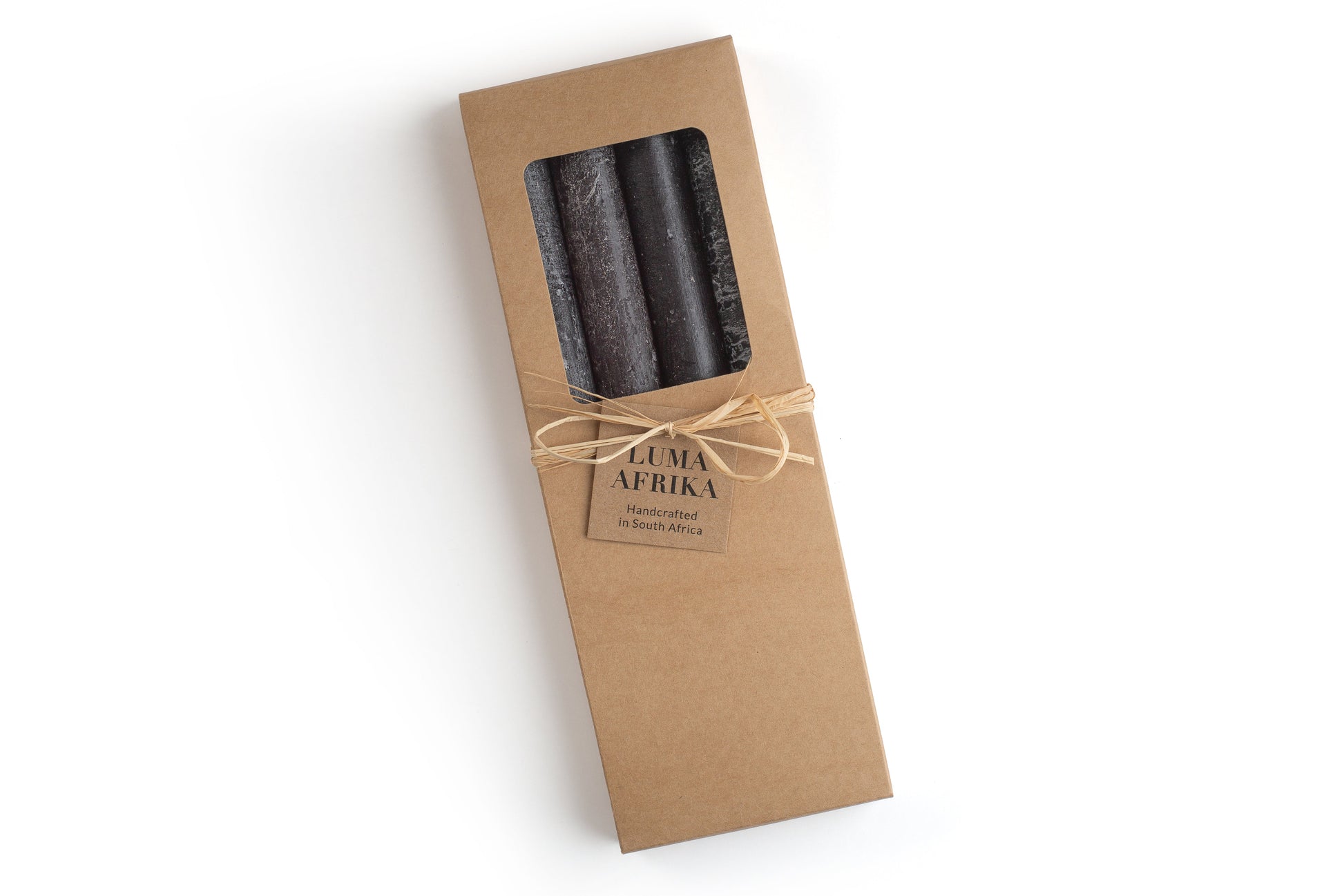 4 black frosted tapers in a kraft bown gift box, ties with raffia and a story card. Luma Afrika. Fair Trade.