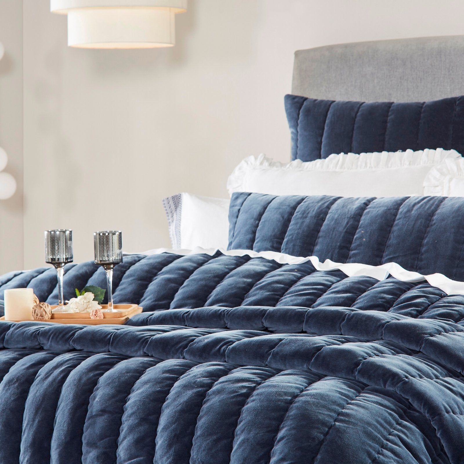 QT-335-11096_2|Luxurious navy velvet quilt with channel stitching on a bed, styled with white ruffled pillows for a cozy bedroom look.